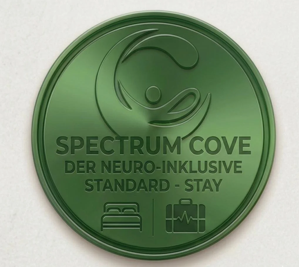 Grüner Medaillenseigen mit einem Symbol eines lachenden Gesichts und Text in Deutsch: "Spectrum Cove, der neuro-inklusive Standard - Stay". Unten sind Symbole eines Bettes und einer medizinischen Tasche.