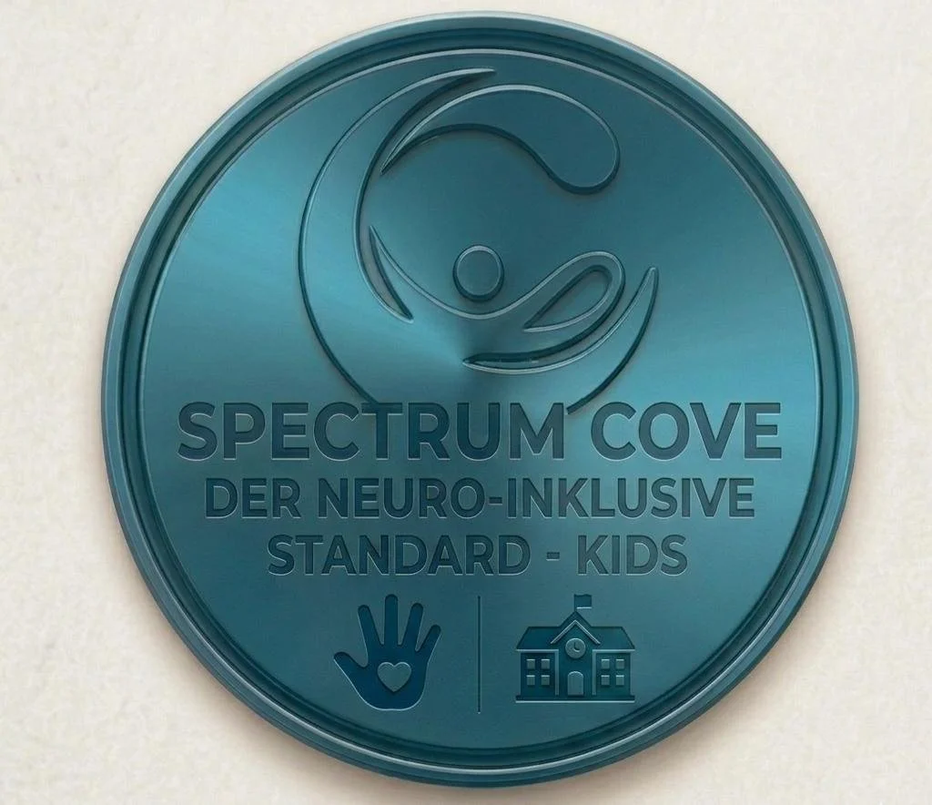 Ein runder, grüner Medaillon mit dem Logo eines lachenden Kindes, Text 'SPECTRUM COVE DER NEURO-INKLUSIVE STANDARD - KIDS' und Symbole einer Hand mit Herz und eines Schulhauses.