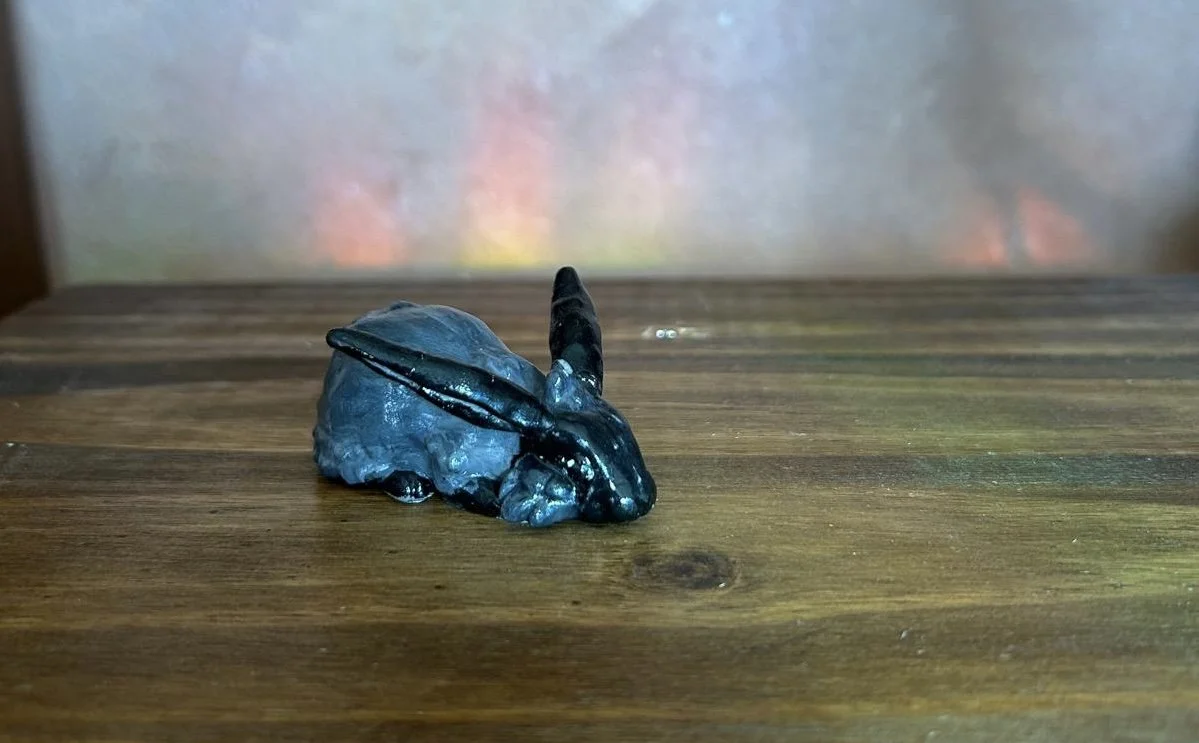 A small black rabbit figurine on a wooden surface.
