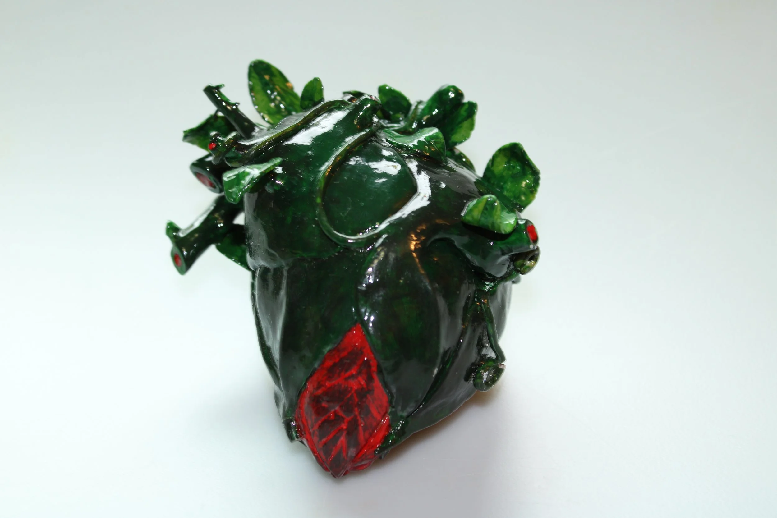 A detailed, crafted sculpture of a human heart made to look like a budding flower, with visible veins and arteries represented by leaves and vines.