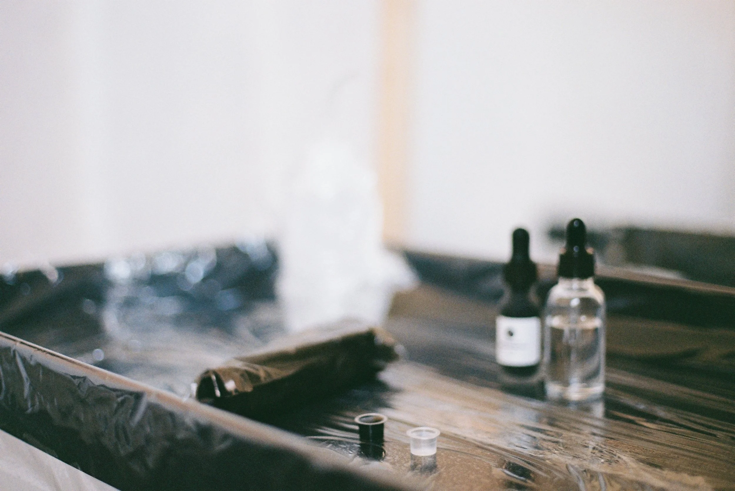 A close-up of a vinyl record player with a small bottle of liquid, possibly ink or cleaning solution, on the turntable.