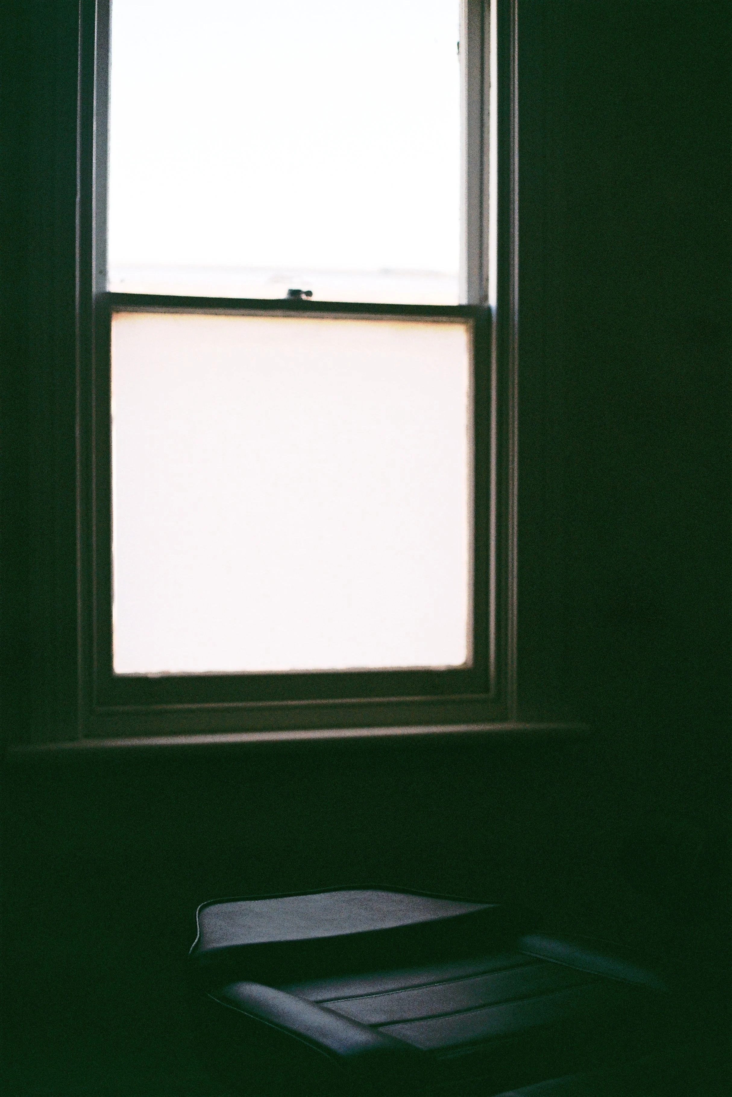 Interior view of a vehicle with a back seat, showing a large window and a plastic panel near the ceiling.