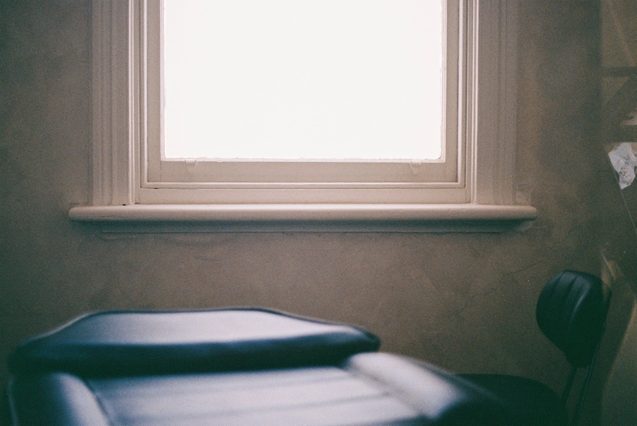 Looking up at a closed window in a ceiling with a white frame, beige wall, and some visible clutter on the floor.