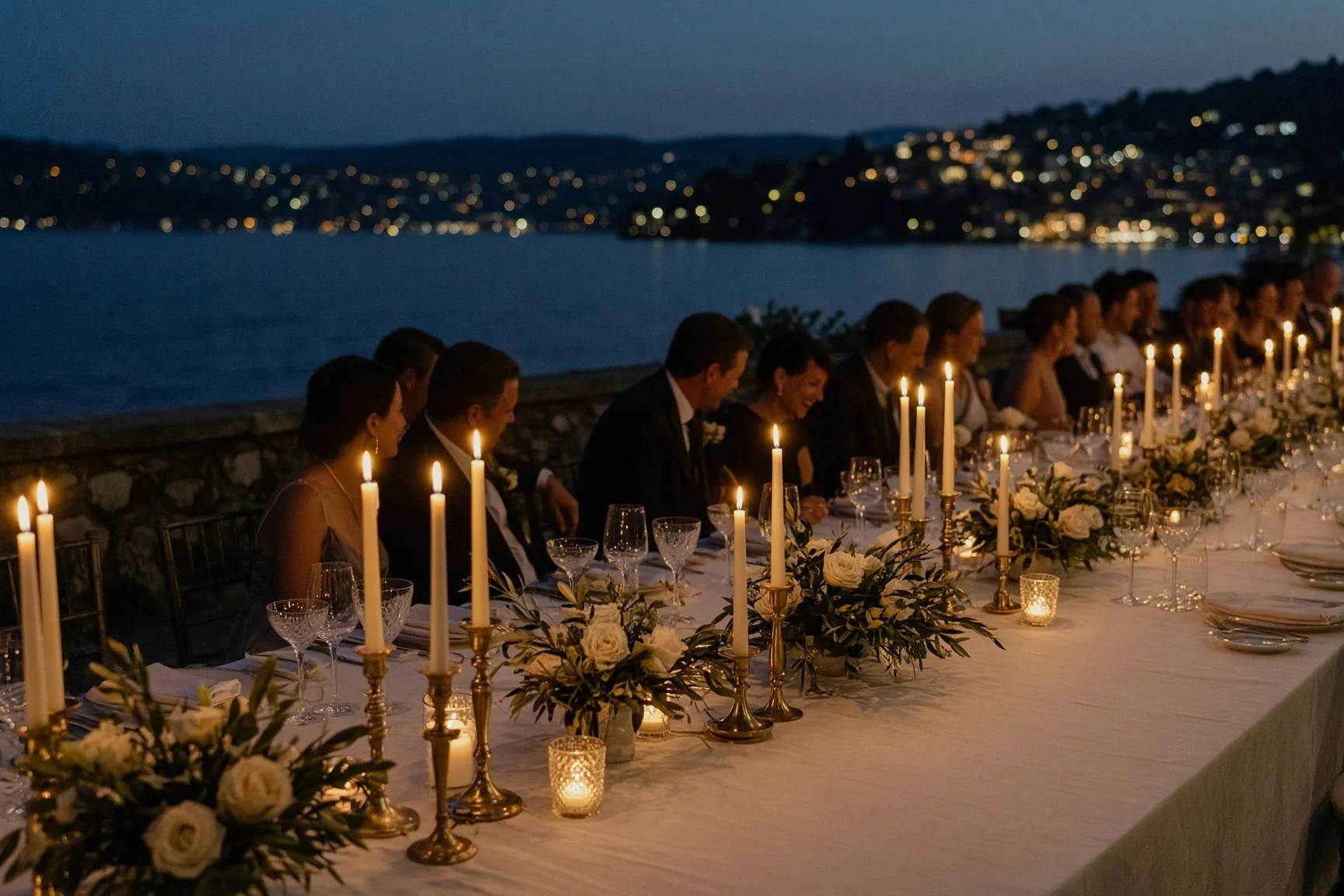 Elegant Lake Como wedding reception at night with candlelit tables, white roses and panoramic lake views.