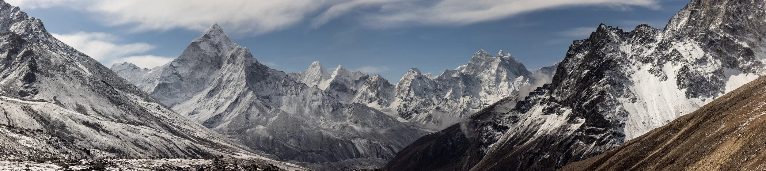 Snow-capped mountains in a rugged landscape under a partly cloudy sky.