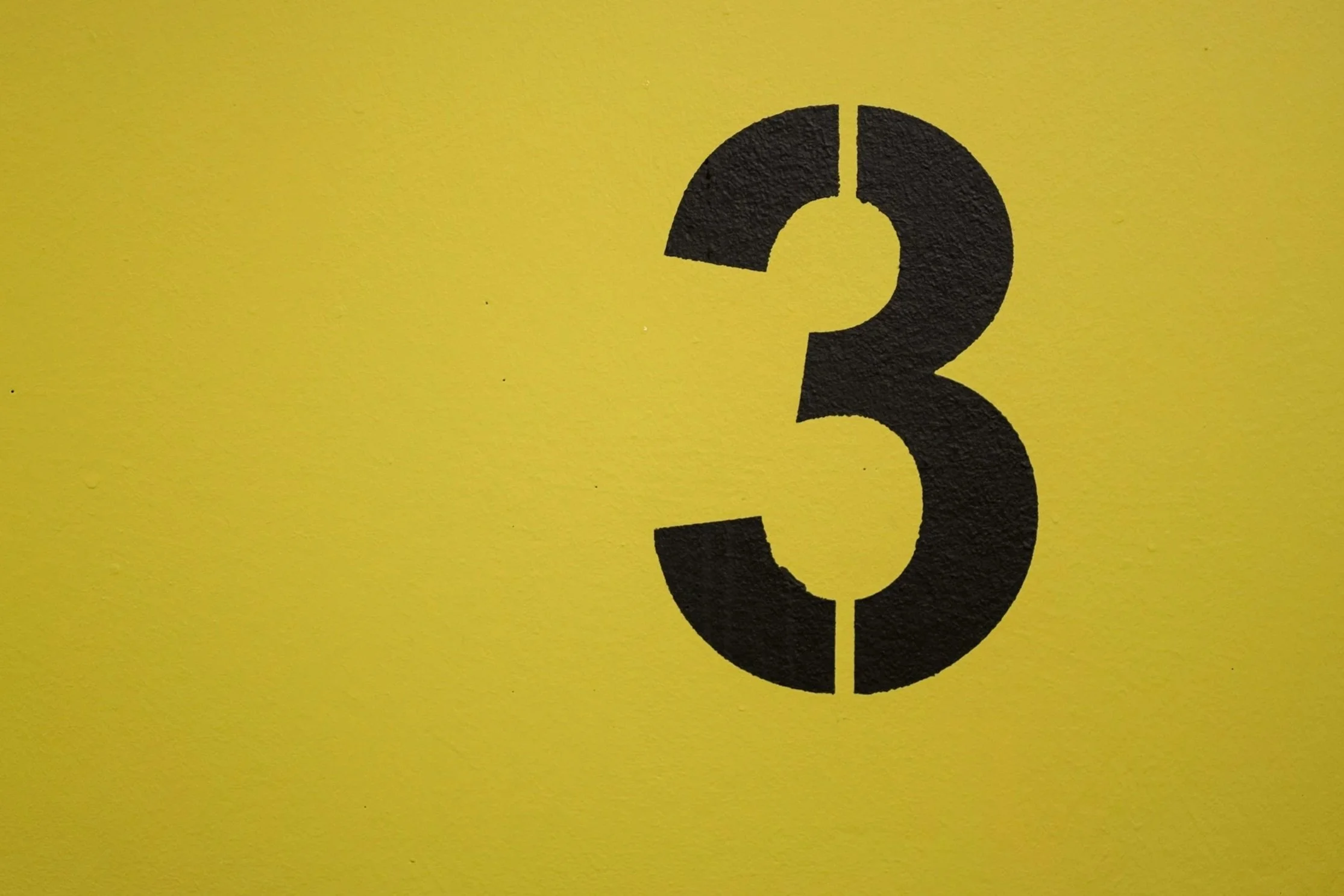 Black number 3 on a yellow wall