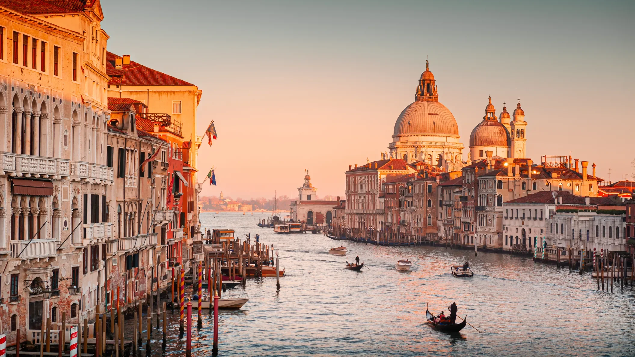 Veduta di Venezia con il Canale Grande, gondole e edifici storici al tramonto.