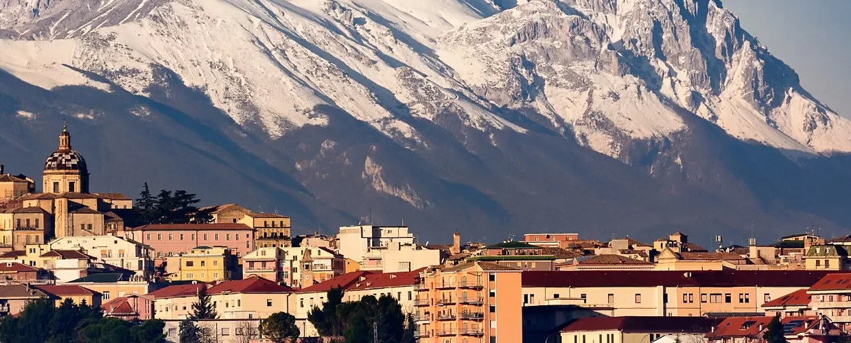 Una città con edifici colorati sullo sfondo di montagne imbiancate.