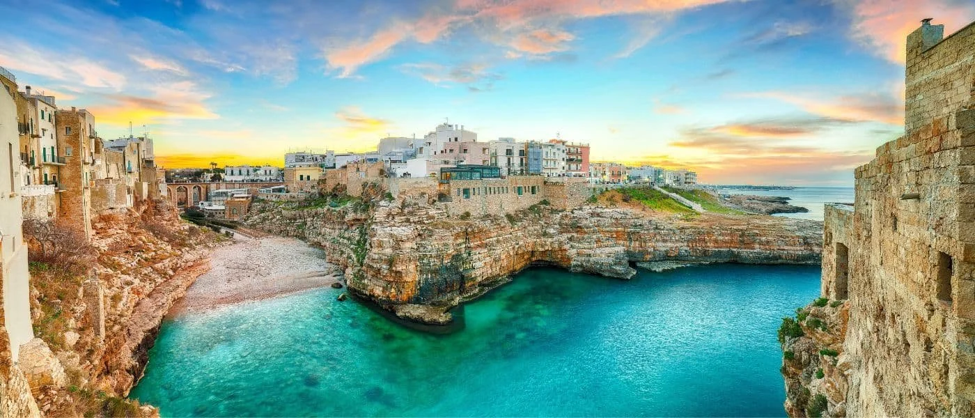 Costa con scogliere e case bianche vicino al mare al tramonto