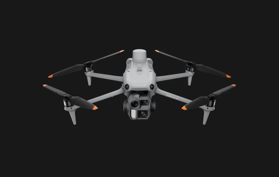 Un drone quadriposto grigio con cinque videocamere nella parte anteriore, posizionato contro uno sfondo nero.