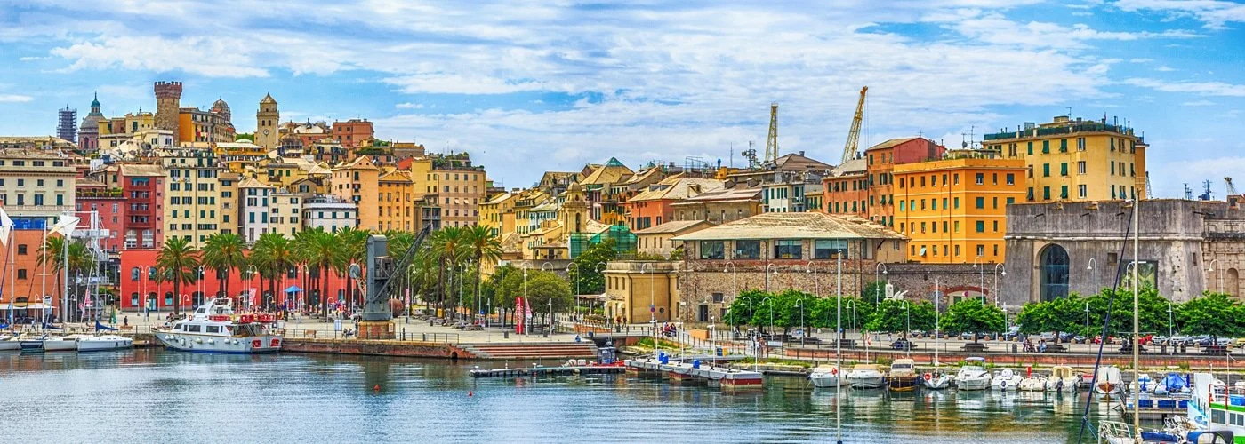Panoramica di un porto con barche e un'area urbana con edifici colorati e un castello in collina