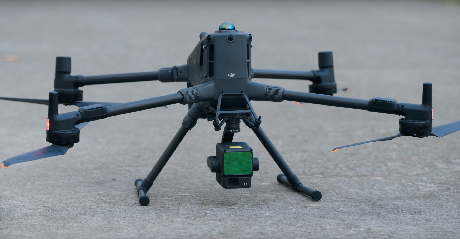 Un drone nero con quattro eliche e una telecamera frontale è posato su un pavimento