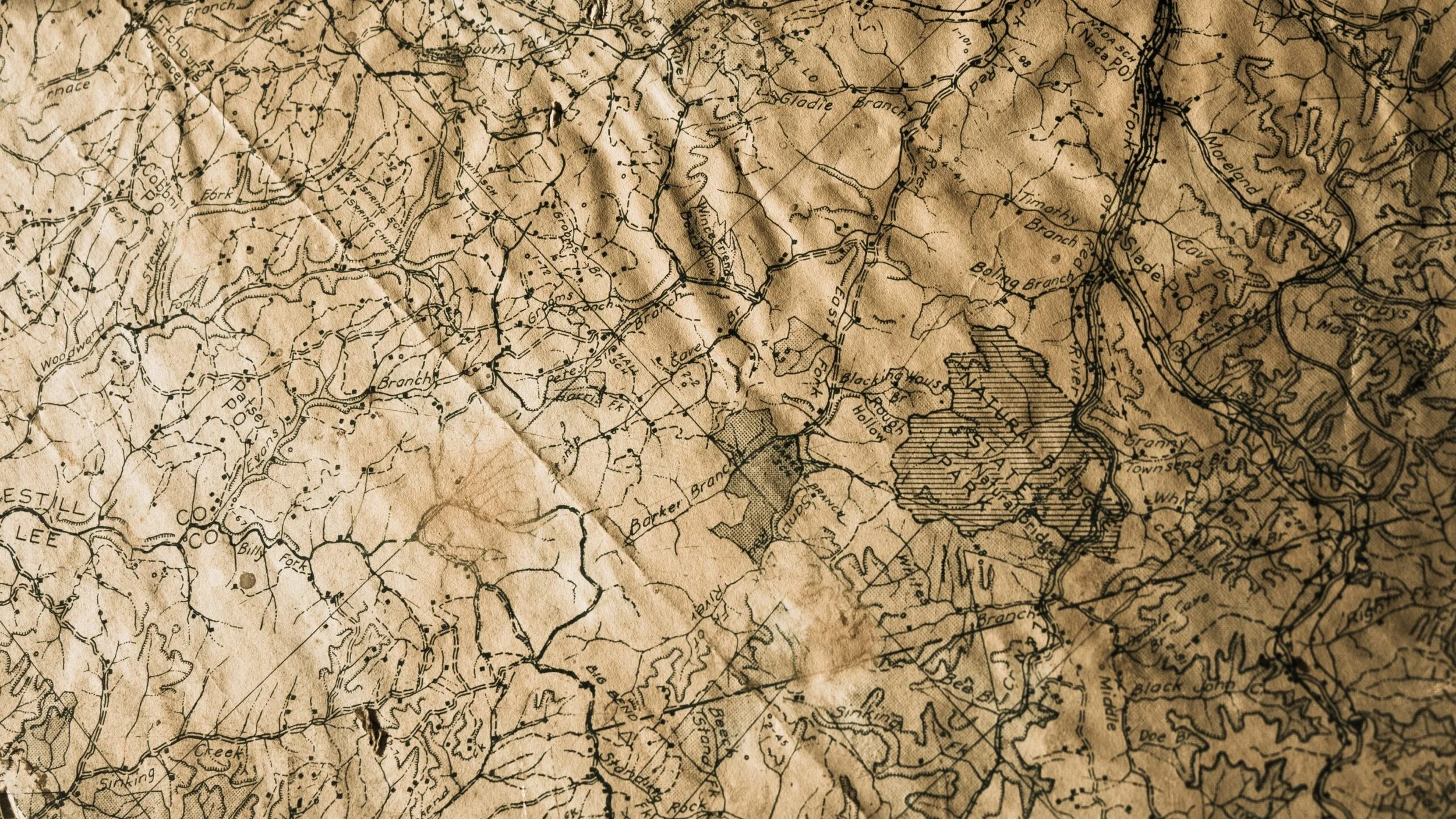 Una mappa antica in stile vintage, dettagliata con linee di terra e nomi di luoghi come 'Glodie Branch', 'Timothy', e 'Blacking Hours,' su uno sfondo marrone consumato.