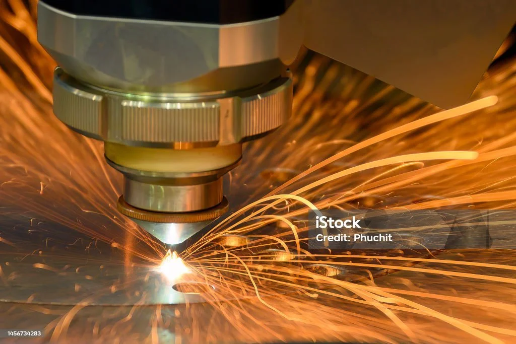 A close-up of a laser cutting metal with sparks flying around.