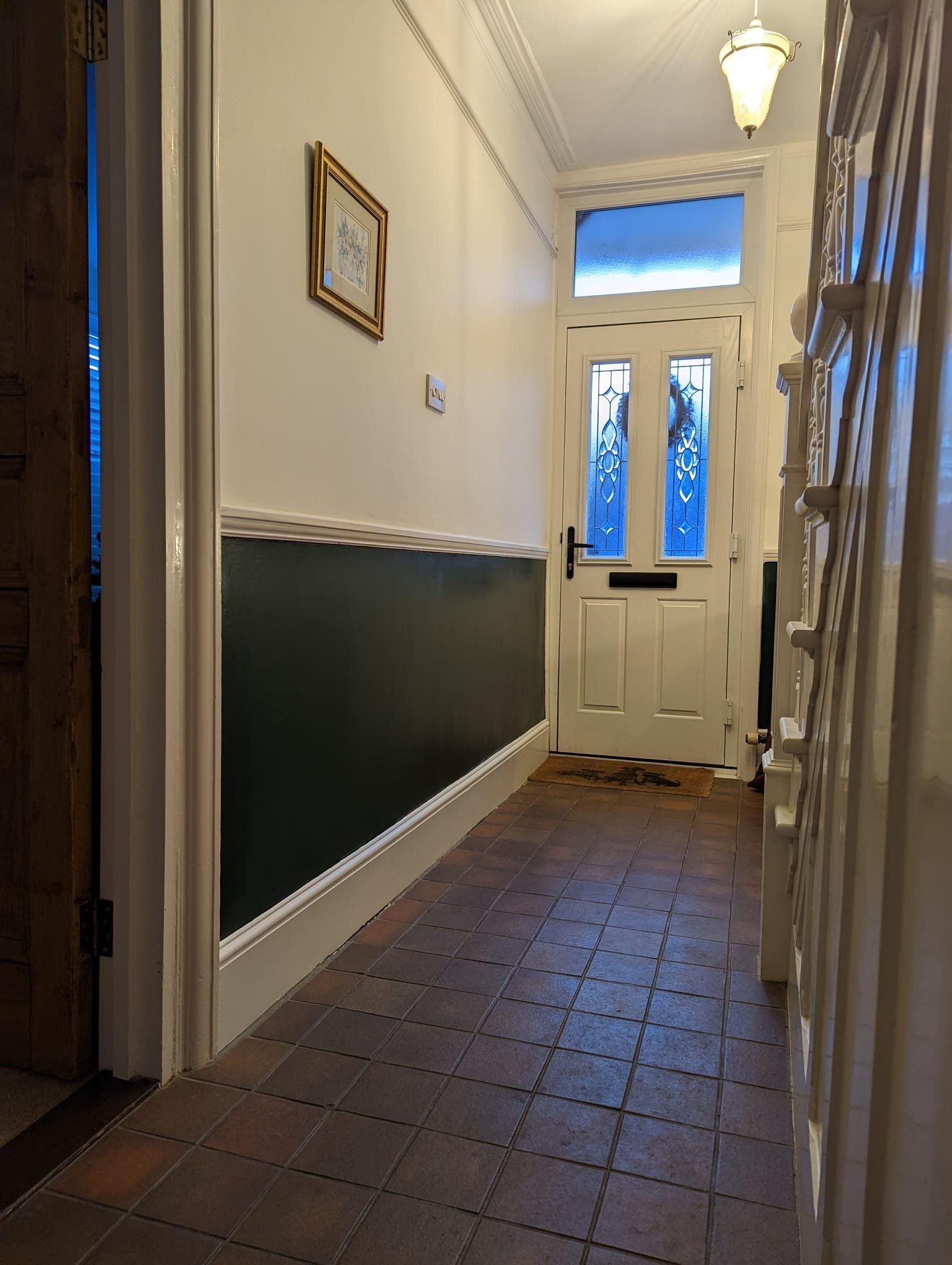 Entryway with a white front door with decorative glass panels, a small window above, tiled floor, and a light fixture hanging from the ceiling.