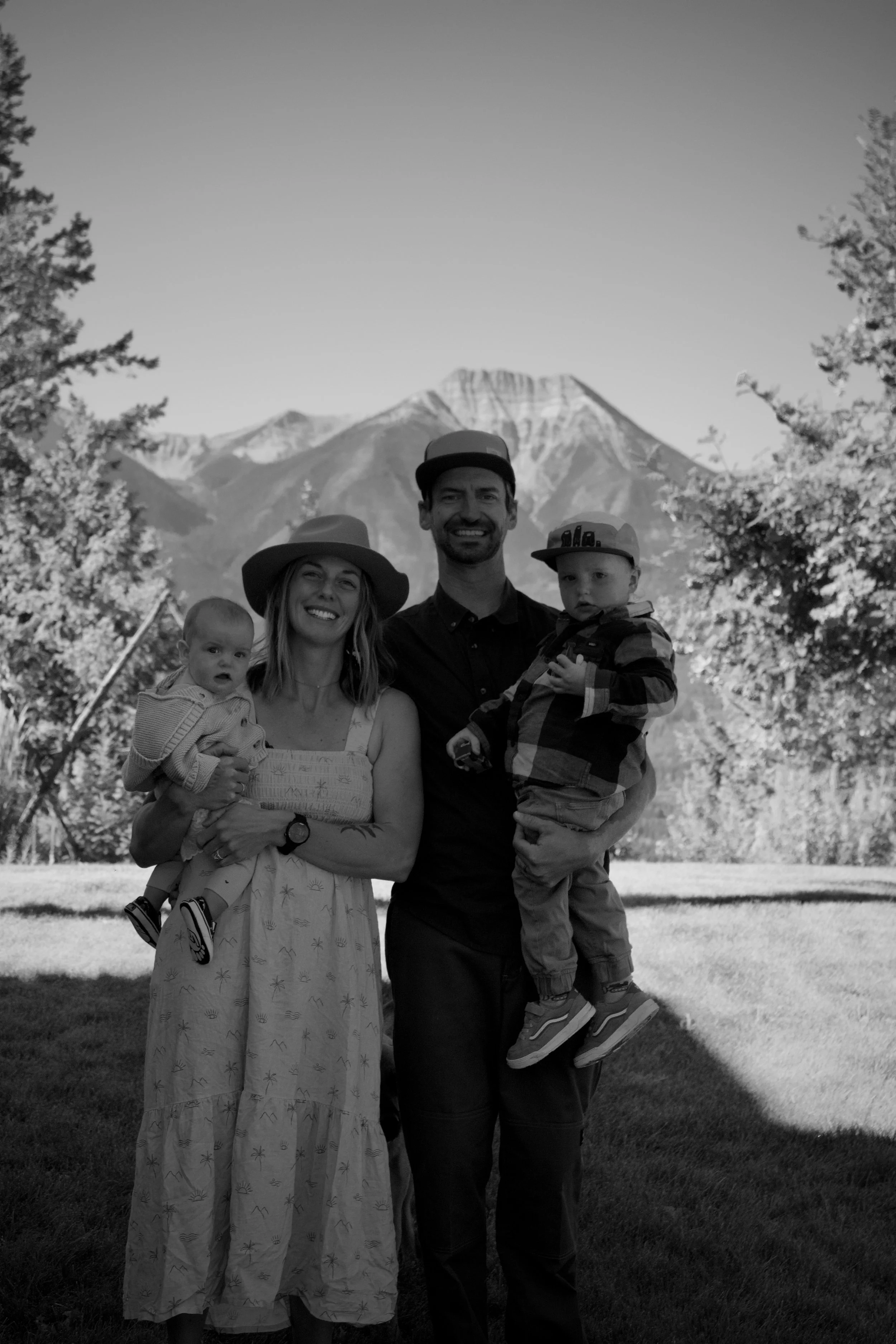 Treeline studio owners family. Black and white smiling with mountains in the background.