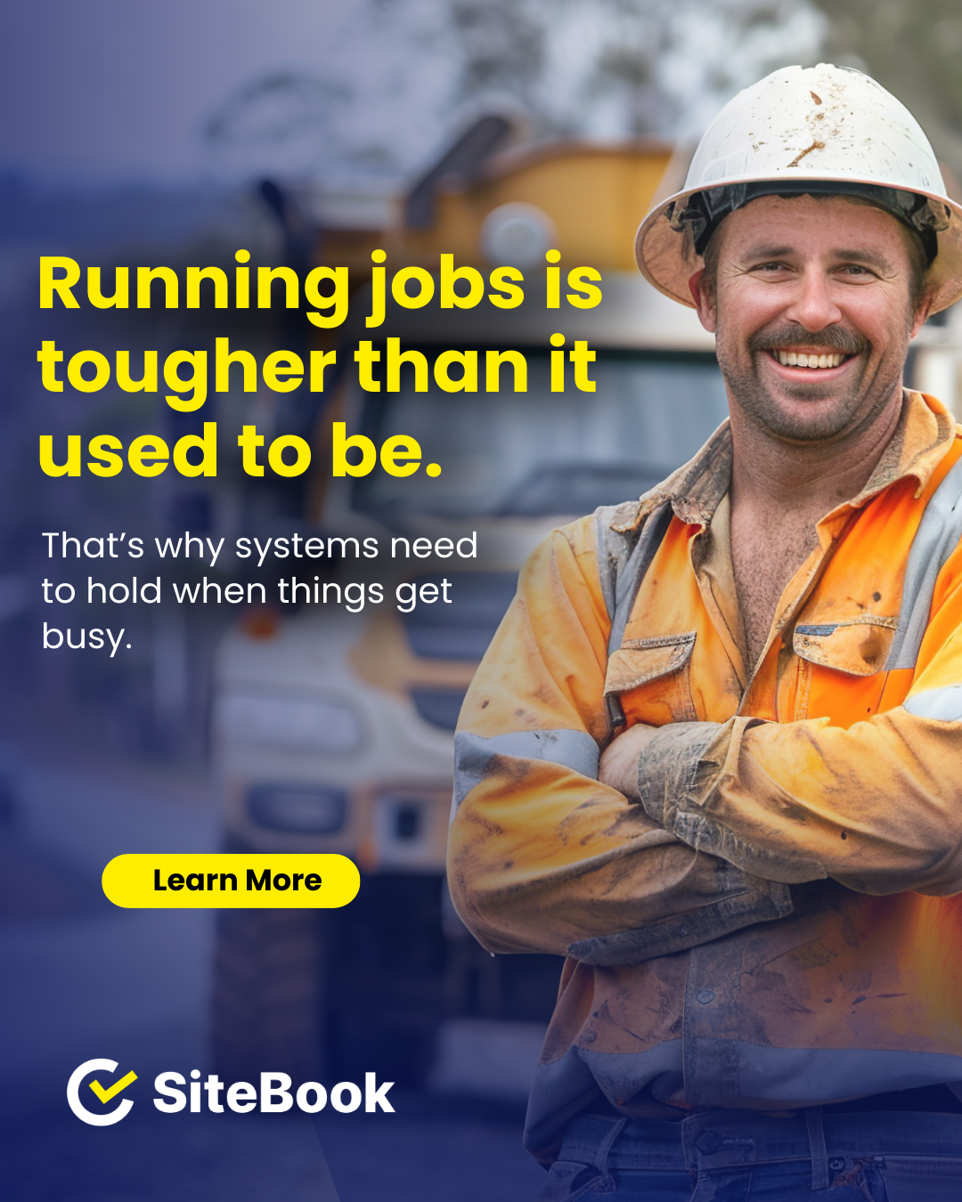 A smiling construction worker wearing a hard hat and reflective vest standing in front of construction vehicles.