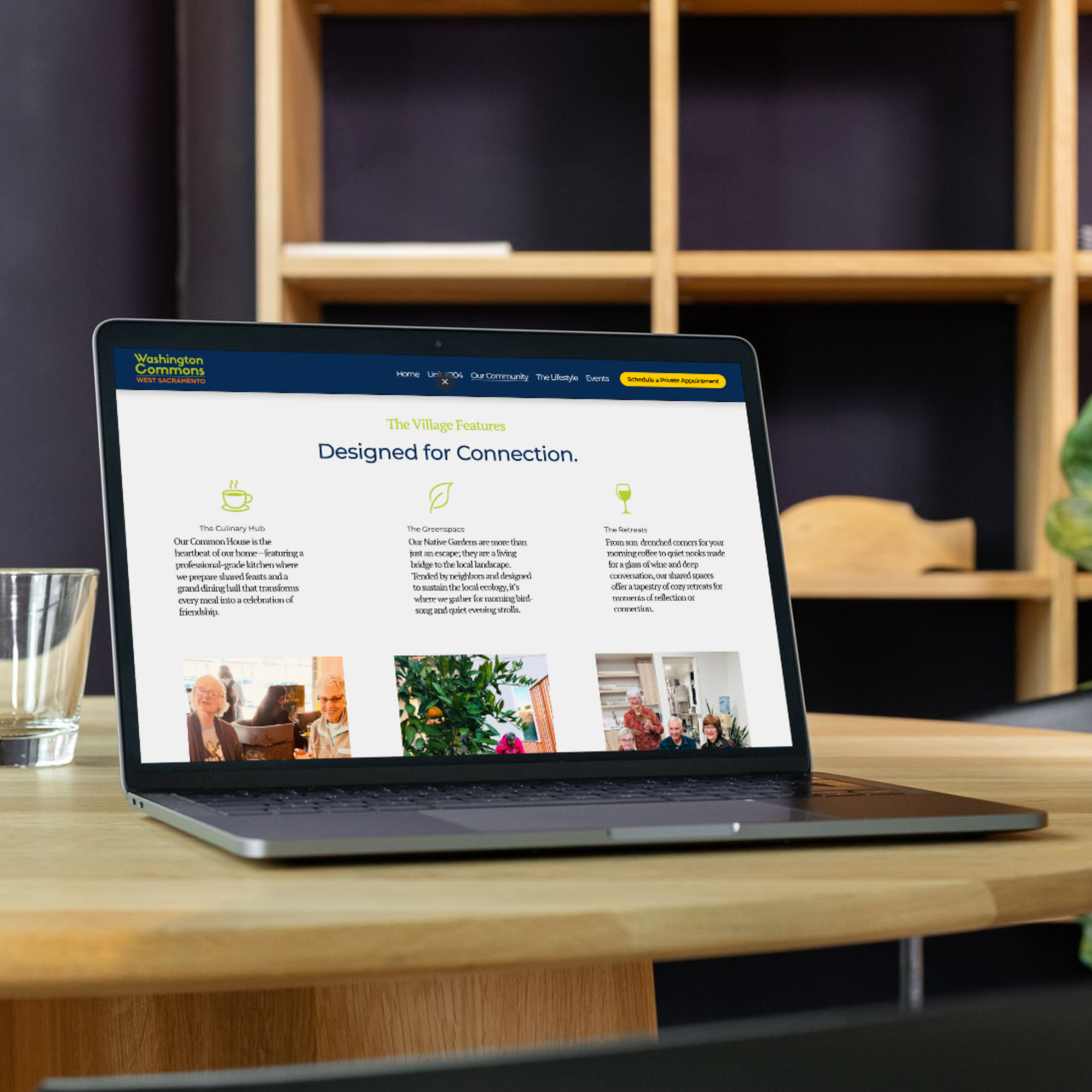 Laptop on a wooden table displaying the homepage of Washington Commons West Sacramento website with a navigation menu and community images, next to a glass of water.