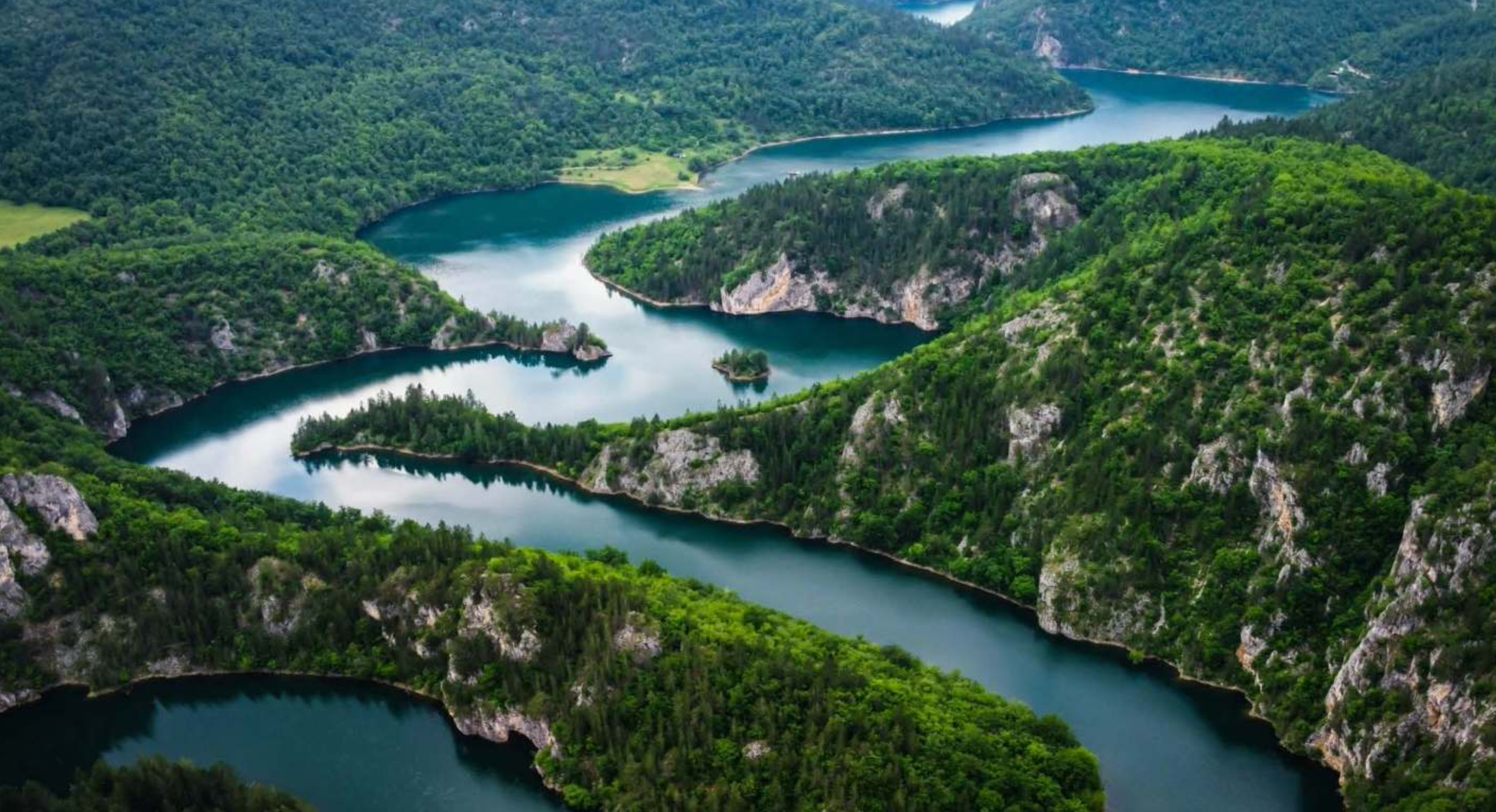 Aerial view of a winding river flowing through lush green forested hills and rocky cliffs. Montenegro. 