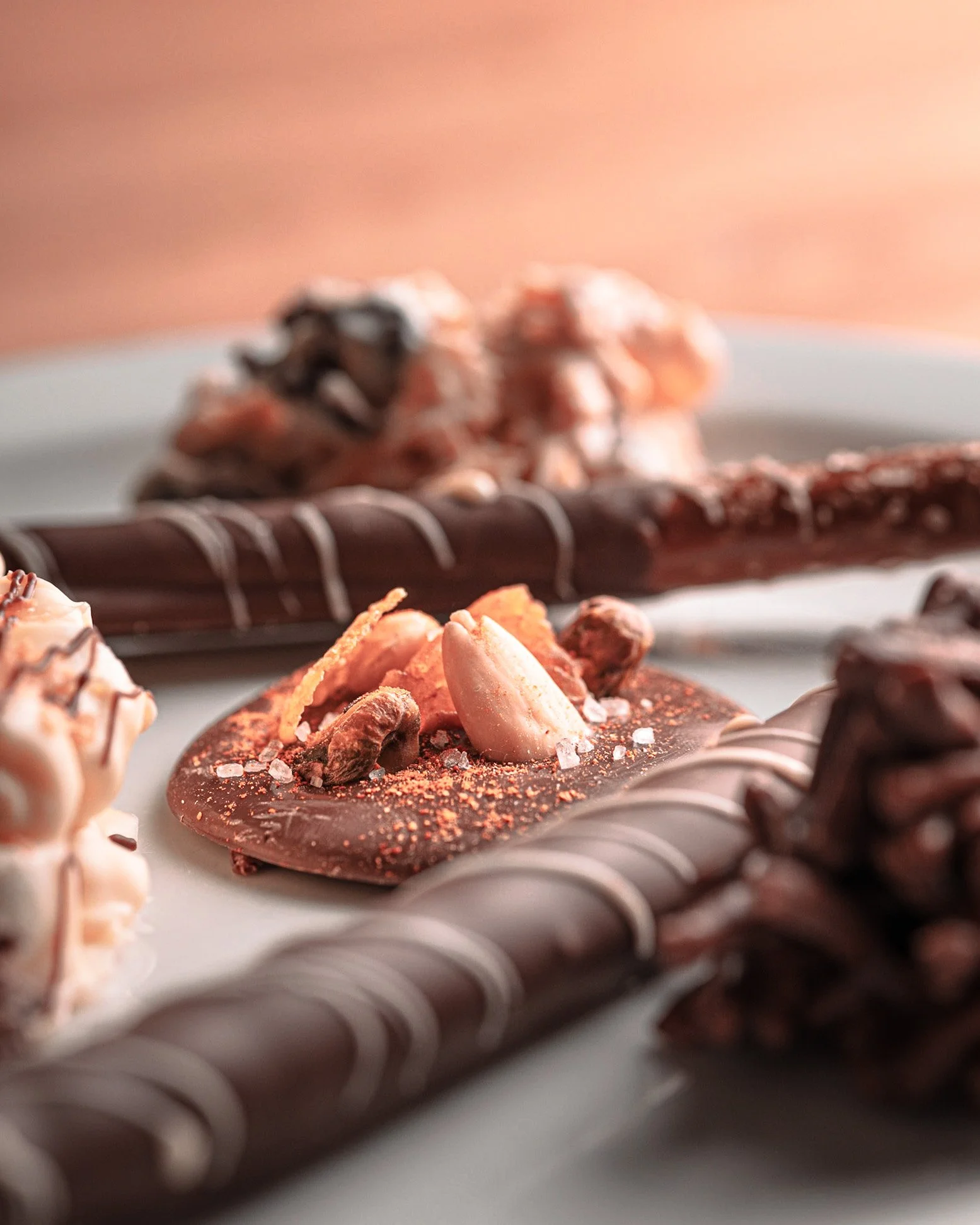 Assorted chocolate confections including a chocolate heart topped with almonds and cocoa powder, chocolate-covered pretzel sticks, and other chocolate treats.