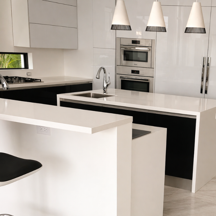 Modern kitchen with white countertops, black and white cabinetry, built-in double oven, a small window, and three pendant lights hanging above the island.