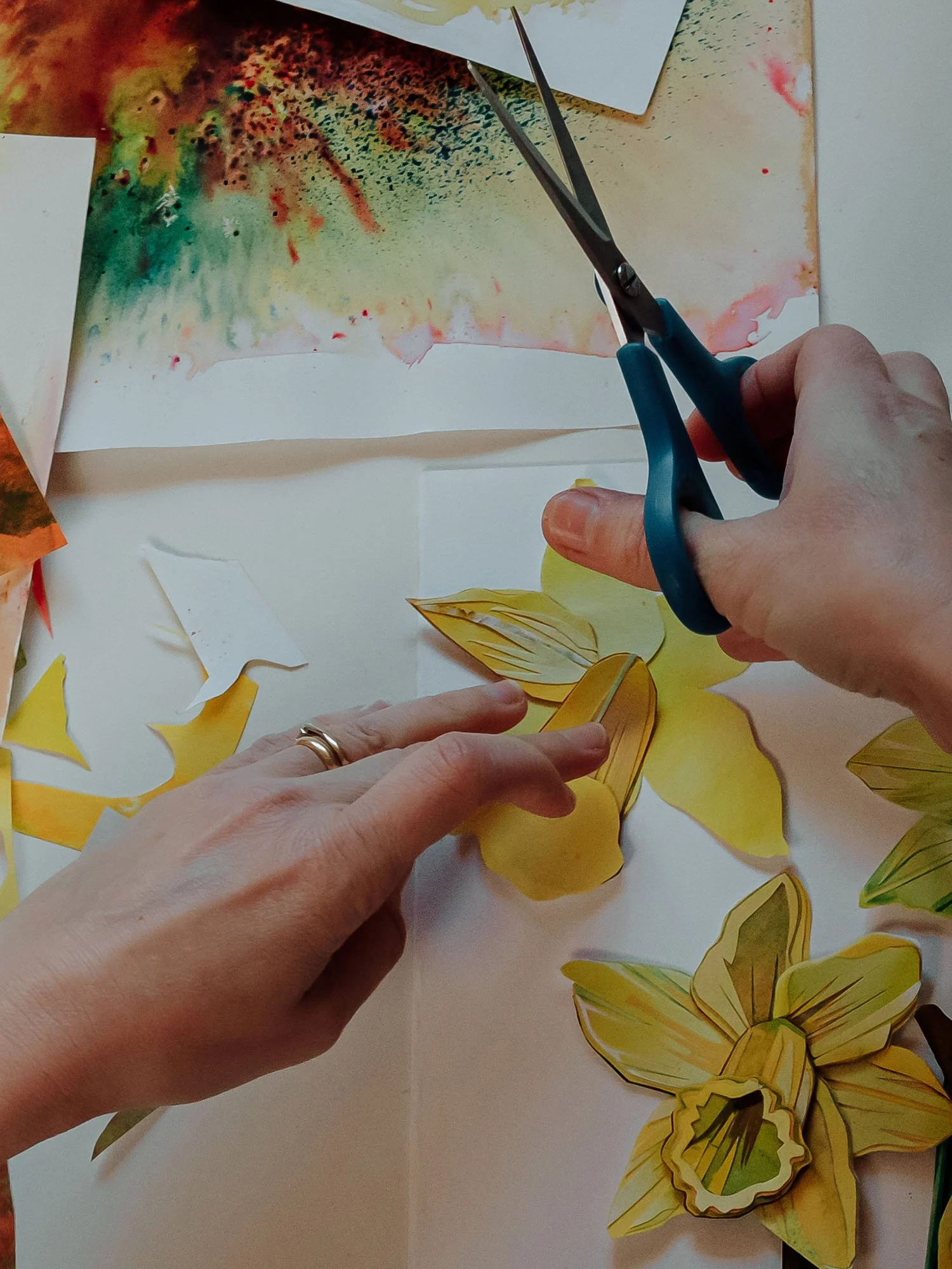 Person cutting and folding colorful paper butterflies with scissors on a table.