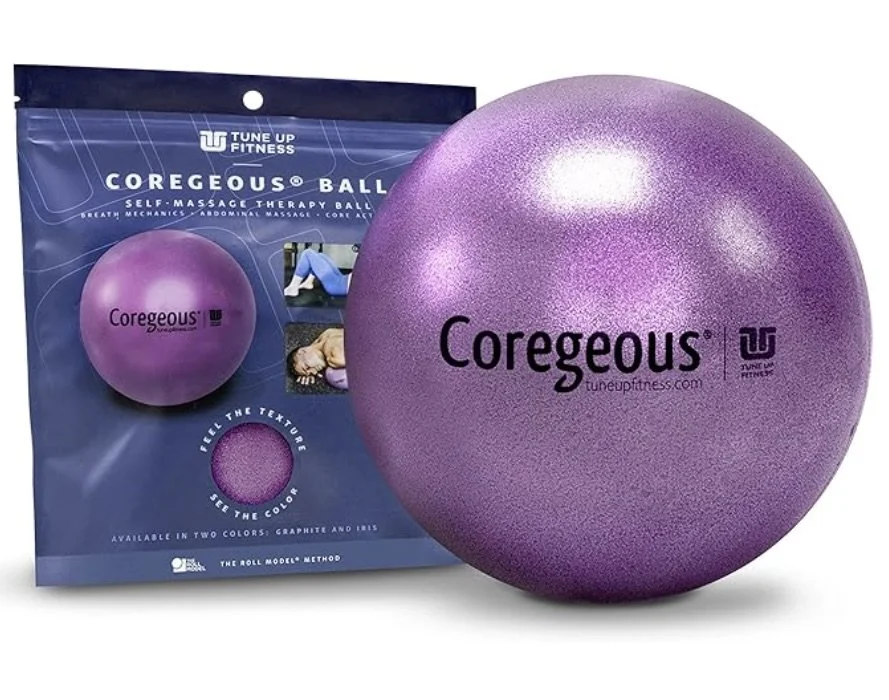 Purple Coregeous self-massage therapy ball with its packaging in the background, labeled as a fitness ball for breathing, abdominal, and core therapy.