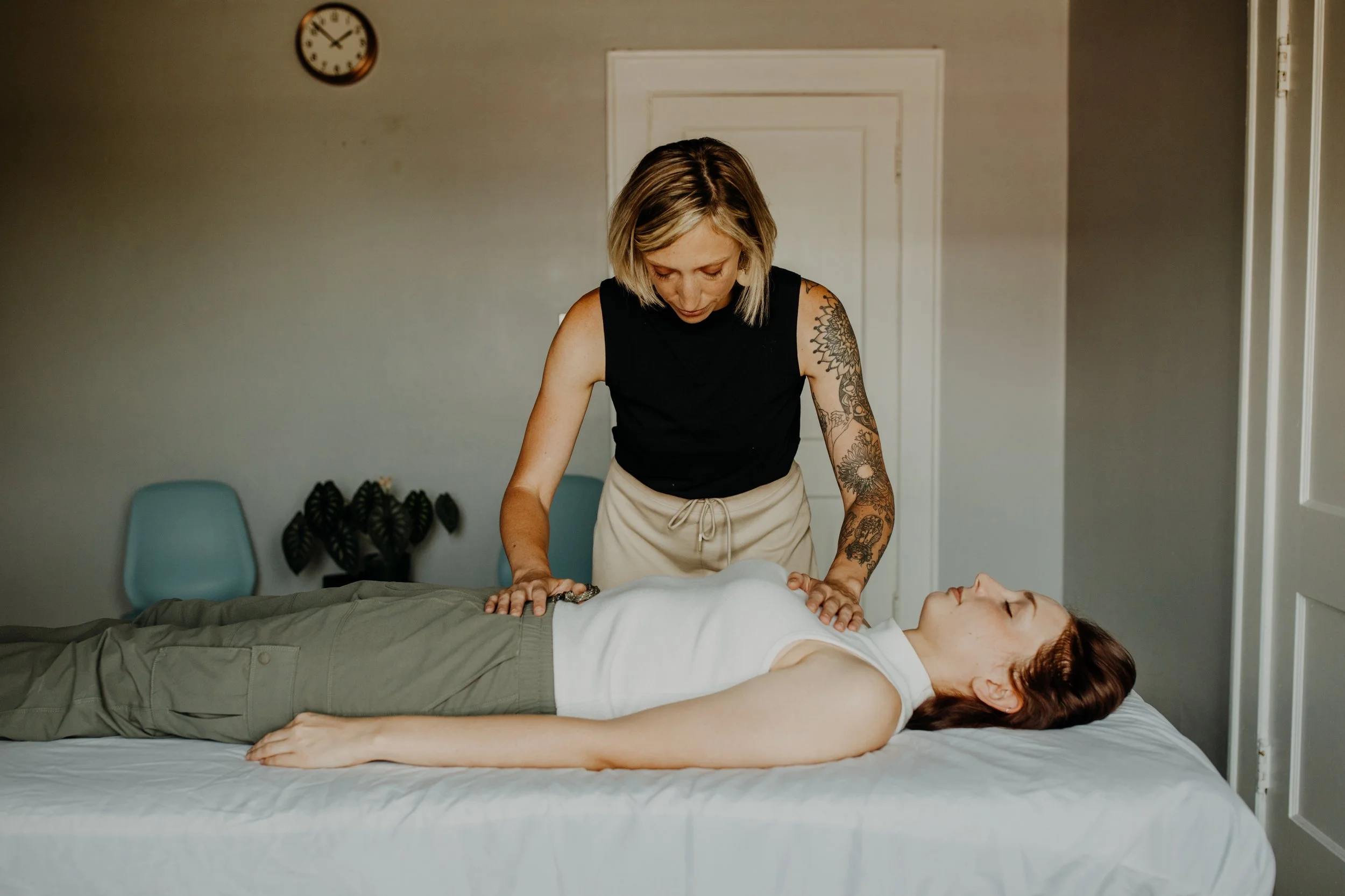 A woman giving a massage on a bed to another woman lying down.
