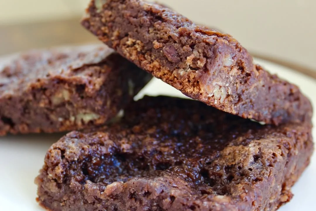 Close-up of chocolate chip cookie dough bars with a gooey chocolate center, with two bars stacked on a white plate.