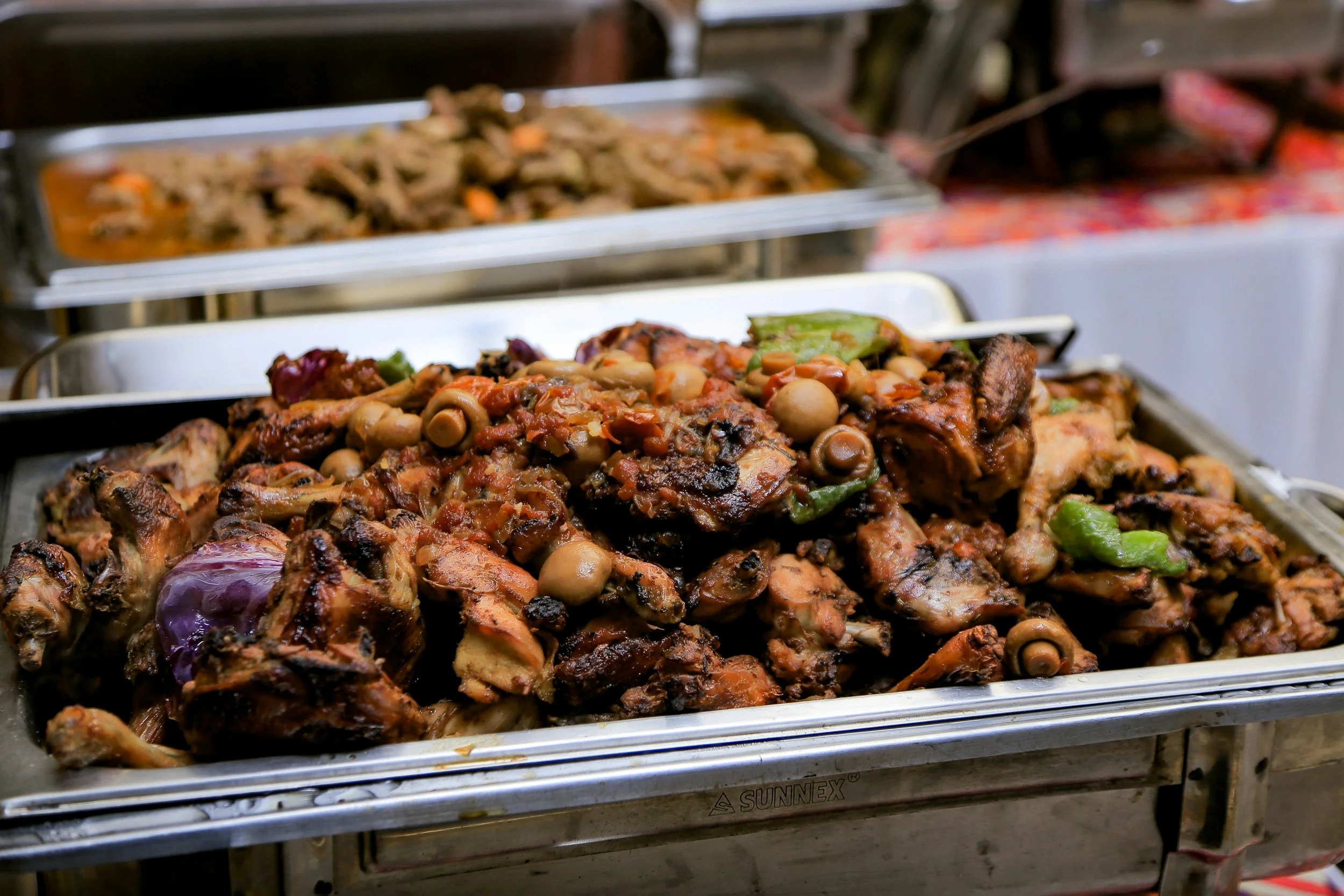 Verschiedene würzige gegrillte Fleischstücke, Gemüse und Oliven in Edelstahlschale bei einer Straßenverkaufsstelle.