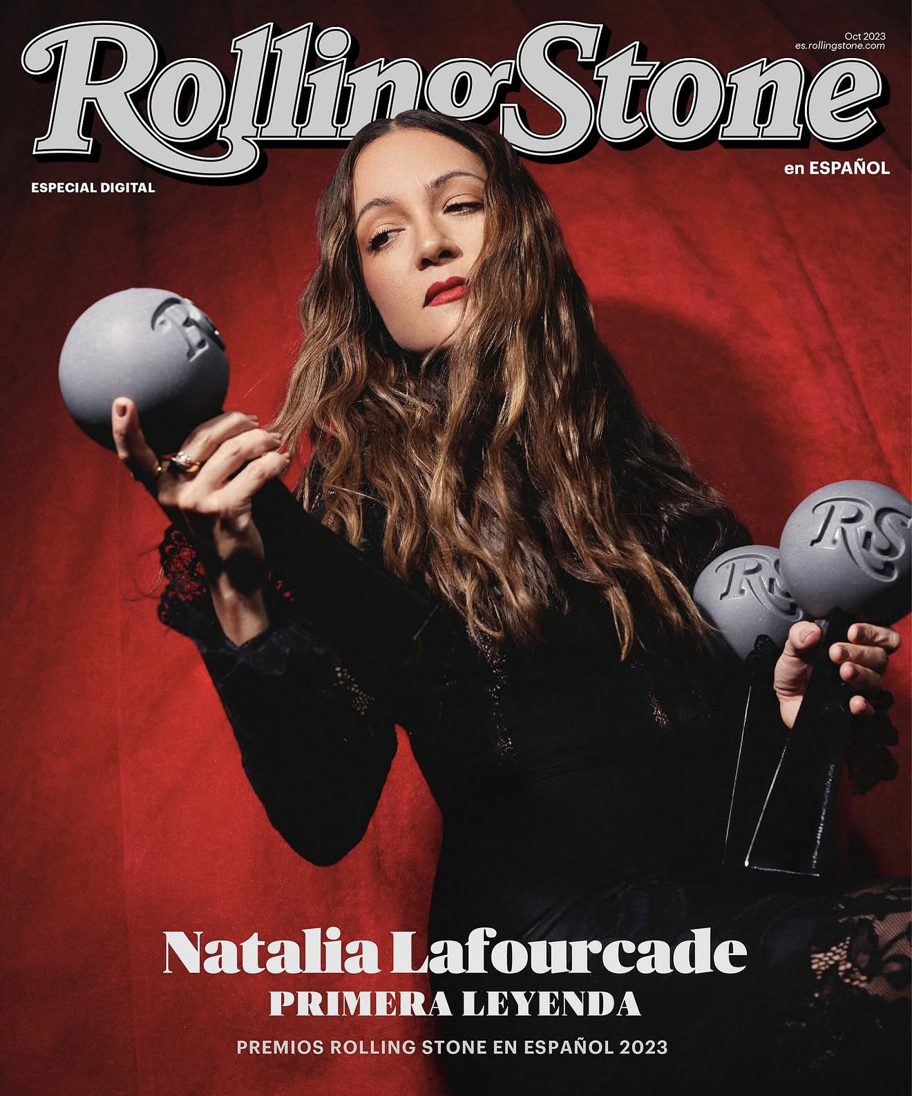 Magazine cover of Rolling Stone featuring Natalia Lafourcade holding gray Grammy-like trophies, with a red background behind her.
