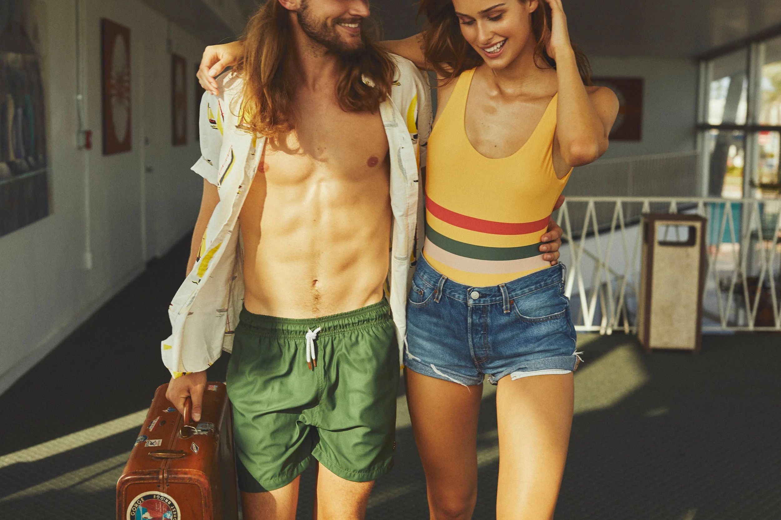 A young man and woman walking together in an airport, smiling and enjoying each other's company.