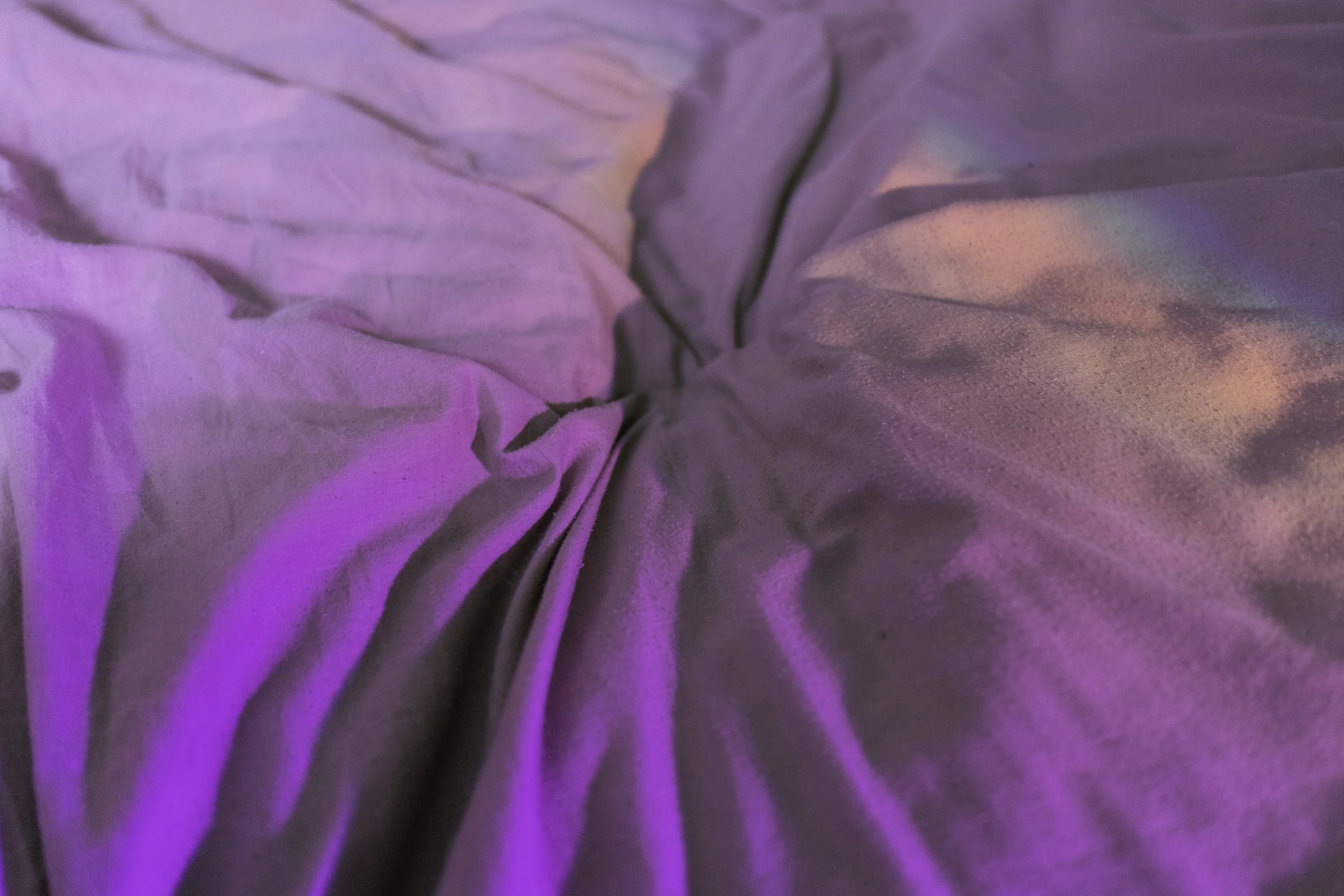 Close-up of pink and purple bedsheets with iridescent highlights, showing detailed texture.