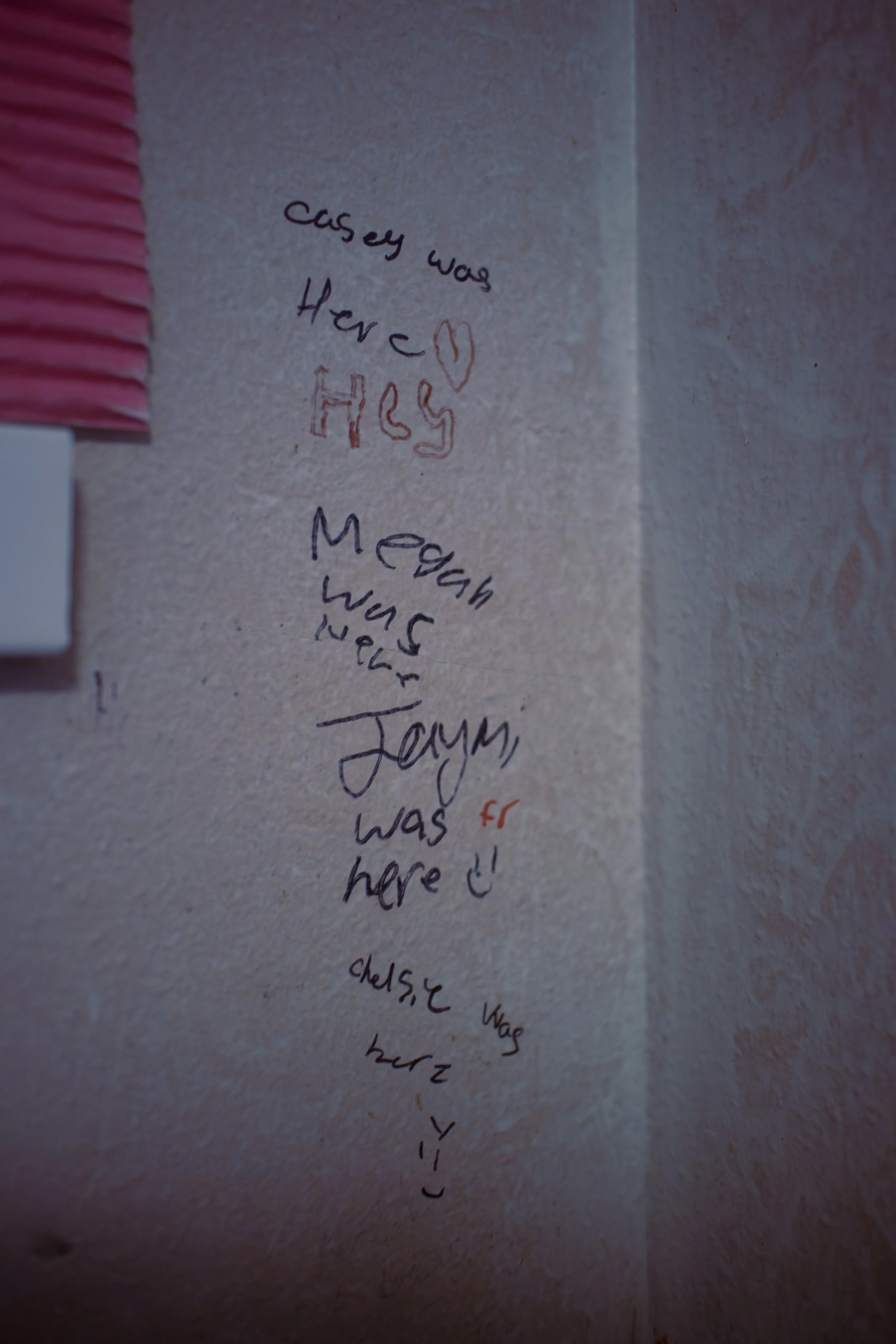 A handwritten note on a wall saying "because was here" with a red heart drawn next to it.