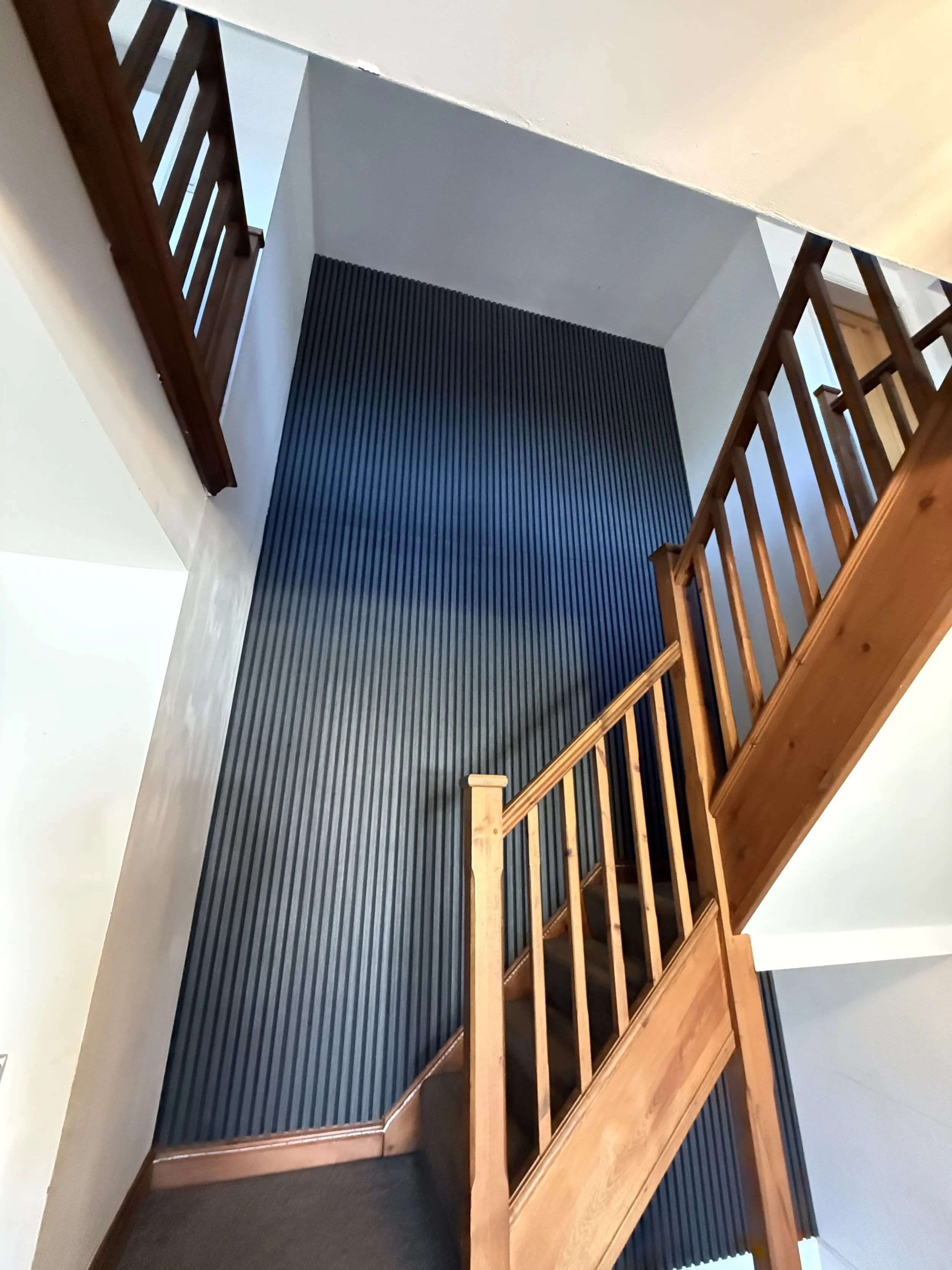 View of a staircase with wooden railings and black textured wall paneling in a modern interior.