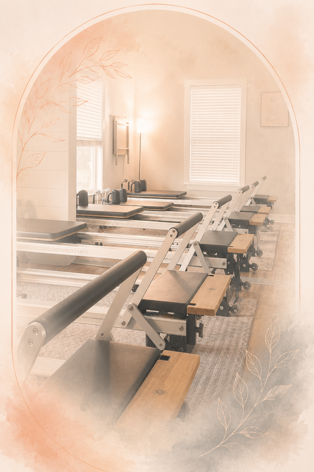 Pilates reformer machines in a bright, airy fitness studio with light-colored walls and large windows with blinds.