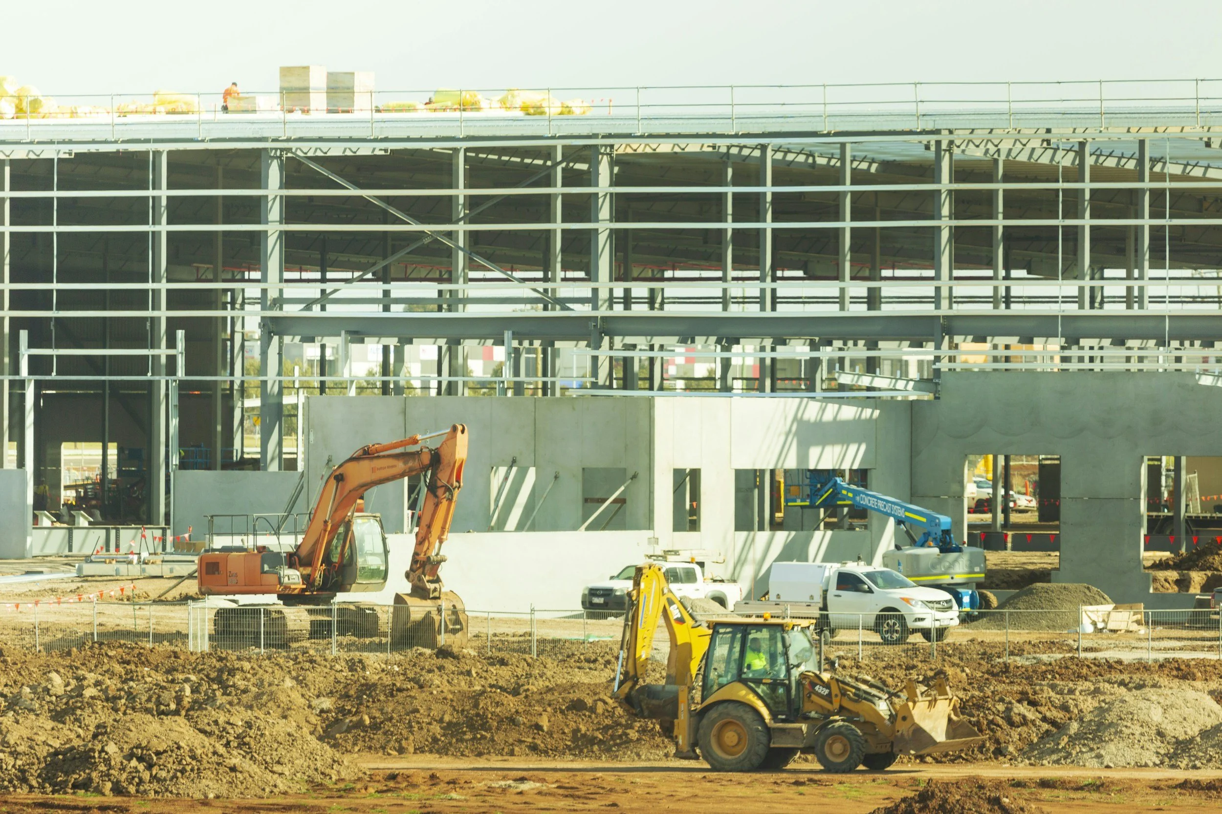 Construction site with excavators, machinery, and a partially built multi-level structure.
