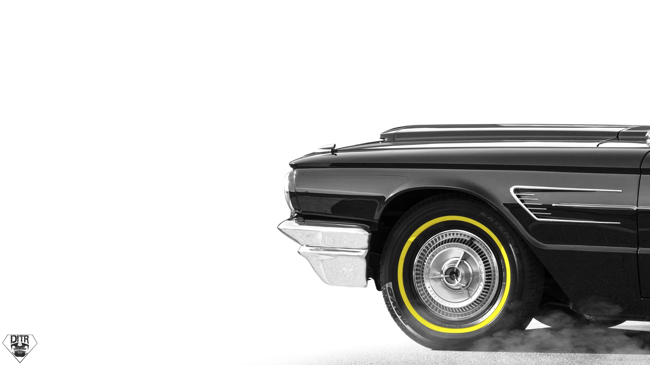 Close-up of the front part of a classic black car with yellow-rimmed wheel, chrome bumper, and grille, set against a white background.
