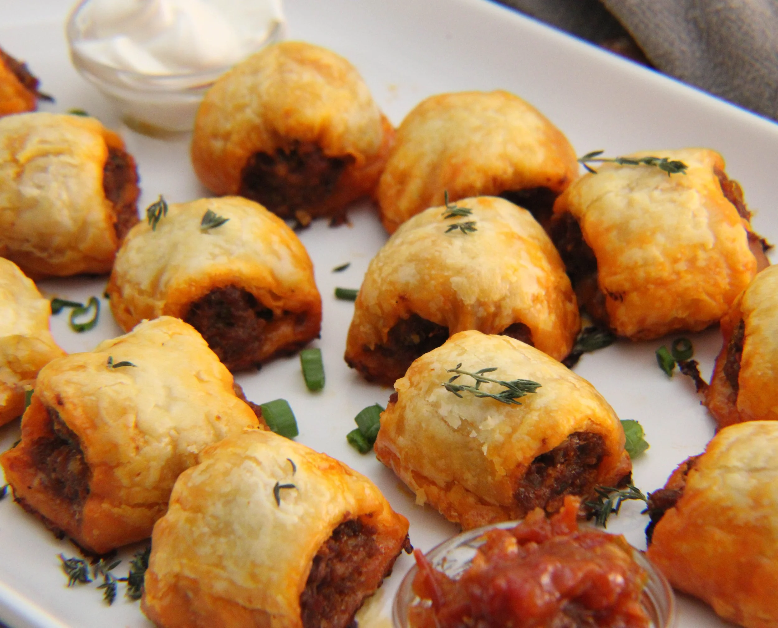 Baked stuffed jalapeño peppers with melted cheese, chopped green onions, and fresh thyme on a white plate.