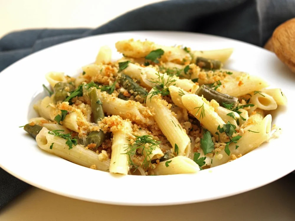 Penne pasta with green beans, fresh herbs and golden toasted breadcrumbs in a creamy shallot sauce.