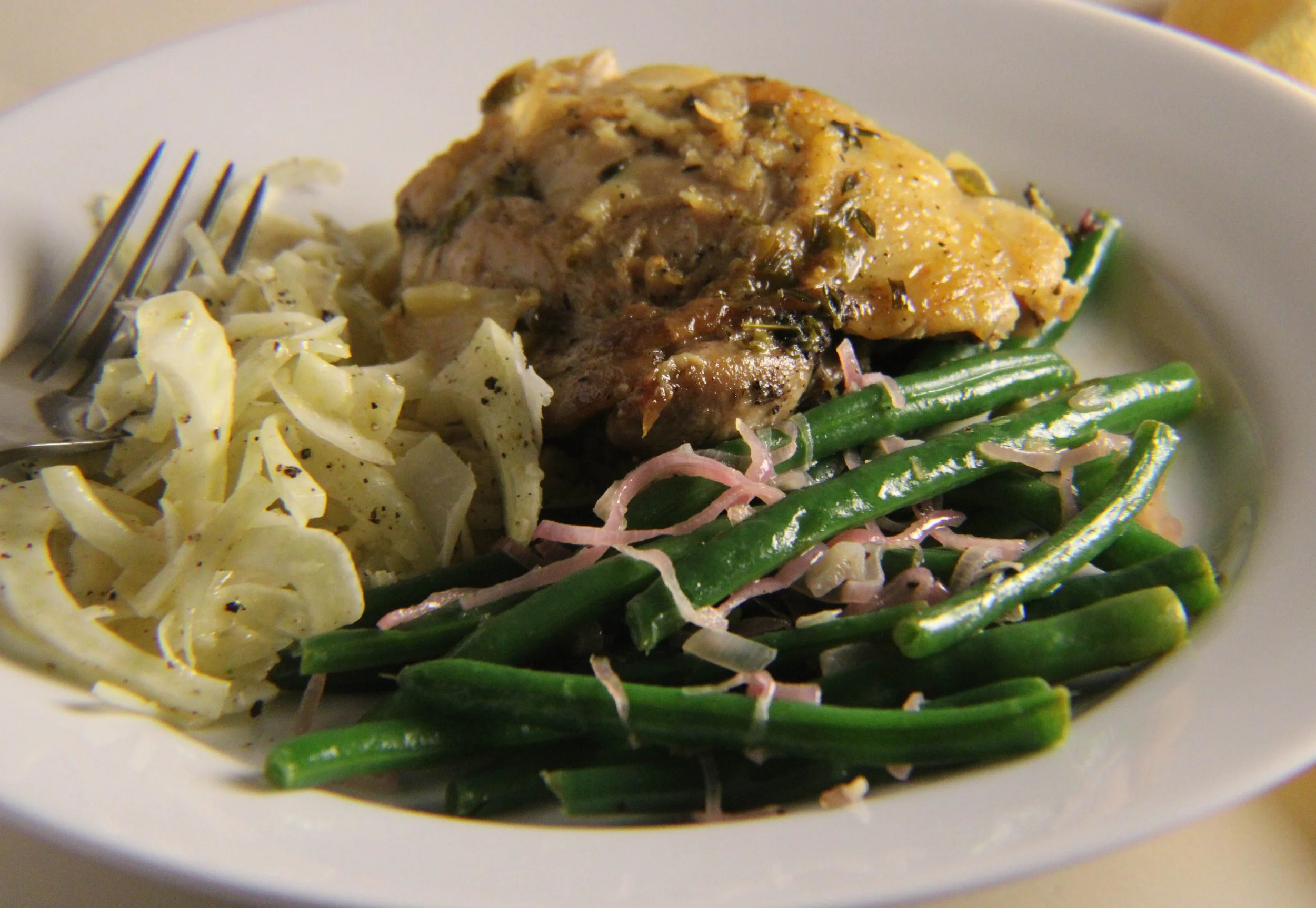 A plate with green beans, shredded cabbage, and a piece of baked chicken topped with gravy.