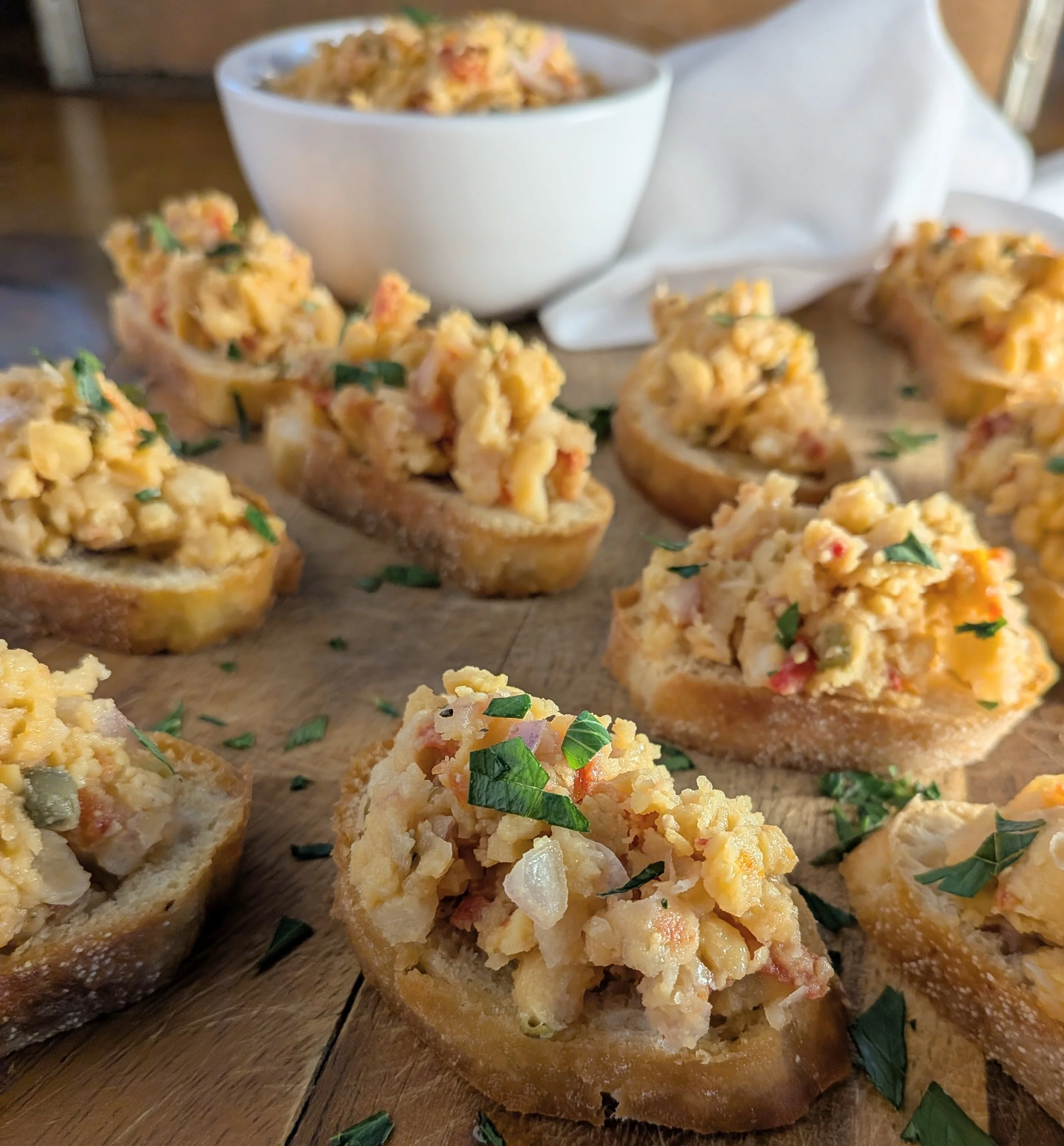Close-up of sliced garlic bread with toppings, including garlic and herbs, on a wooden surface.