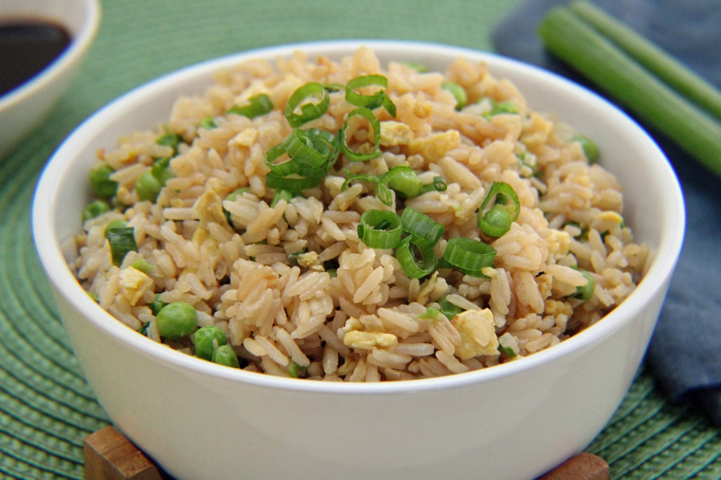 A white bowl filled with fried rice topped with chopped green onions