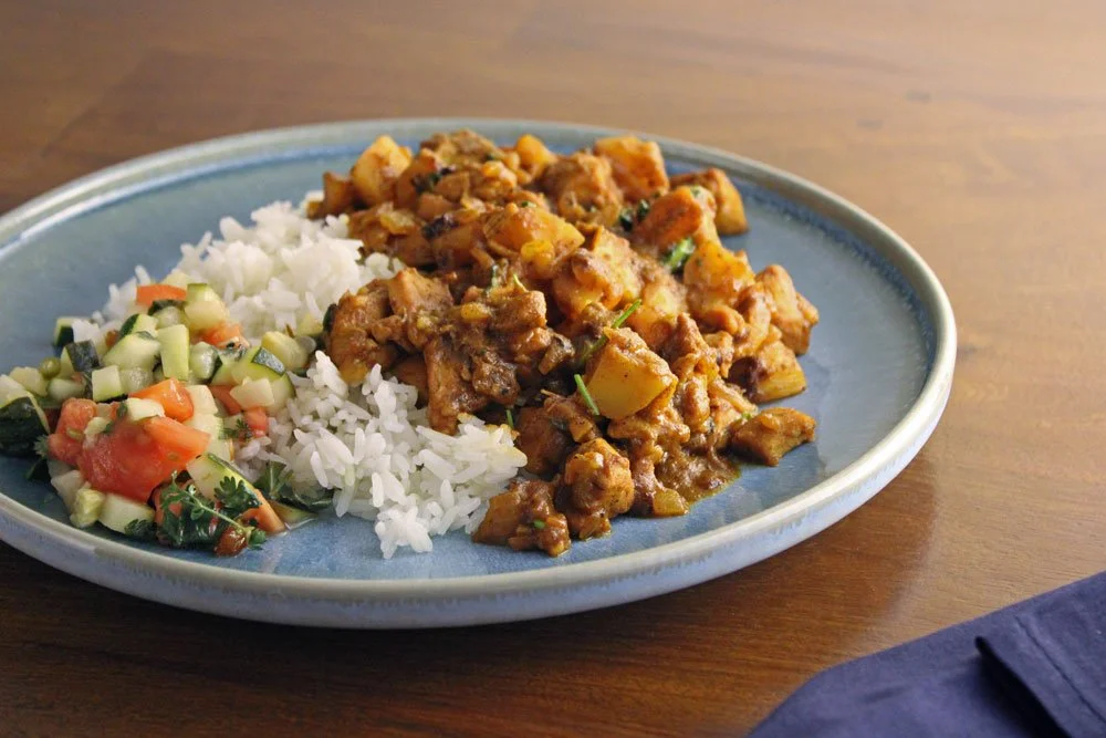 Cape Malay chicken curry with tender chicken and potatoes in a fragrant spiced sauce, served with white rice and warm zucchini sambal.