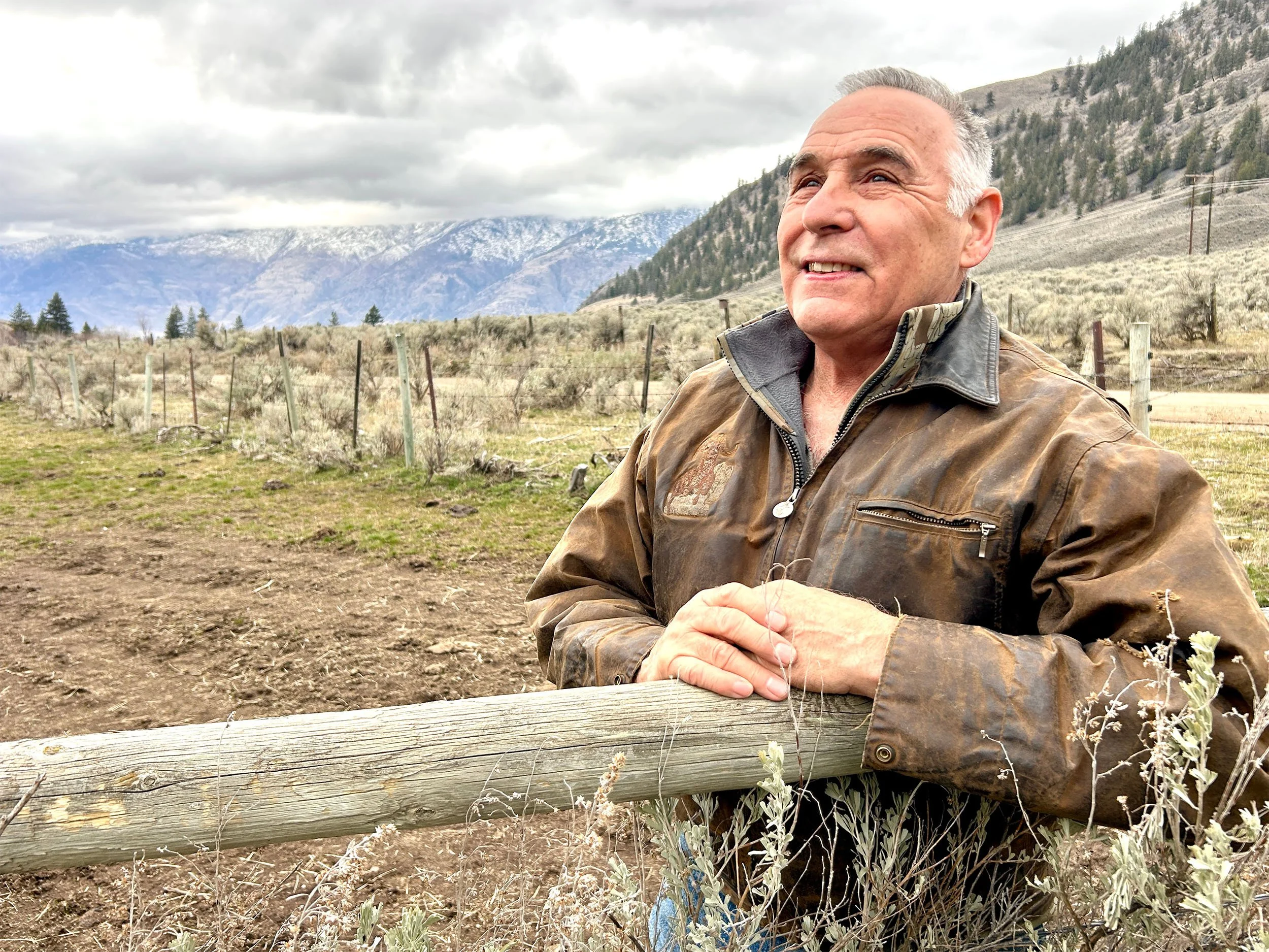Casey Cawston, co-founder, leaning against a fence with Southern Okanagan landscape in the background