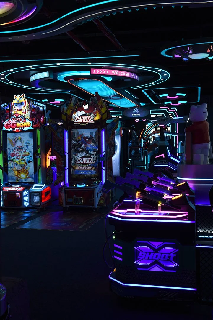 An arcade with neon lights and various gaming machines, including a Super Go Bong and Hello Carbot arcade games, with a dark atmosphere and colorful LED lighting.