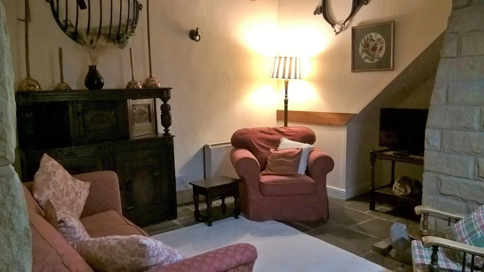 One of two warm and cosy sitting rooms at The Old Stables Buxton, featuring comfortable seating, soft lighting, and period character—ideal for relaxing after a day in the Peak District.