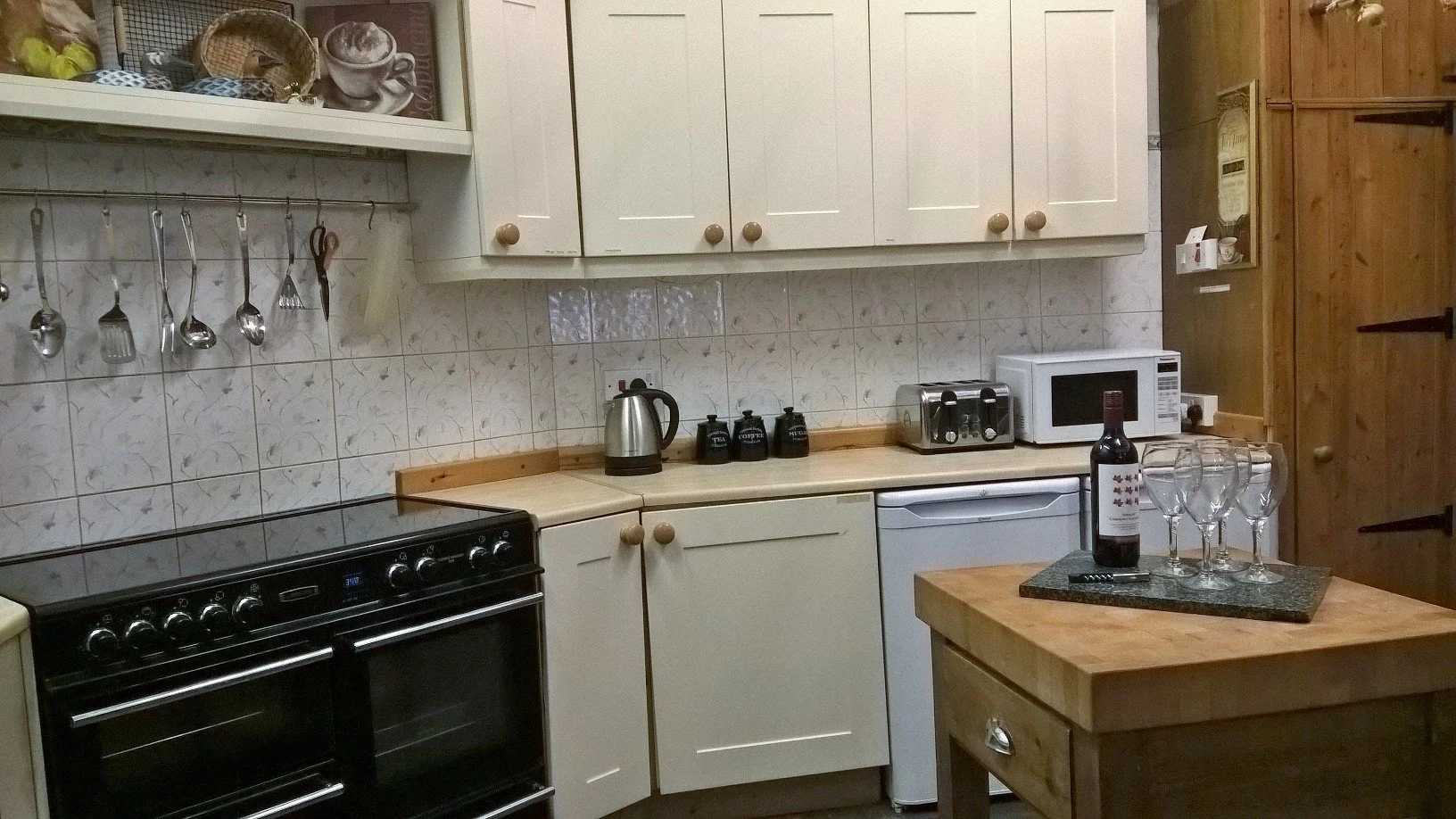 Fully equipped kitchen at The Old Stables Buxton, designed for groups of 10 with ample counter space, large oven, wooden cutting board on an island with wine and modern amenities for self-catering holidays.