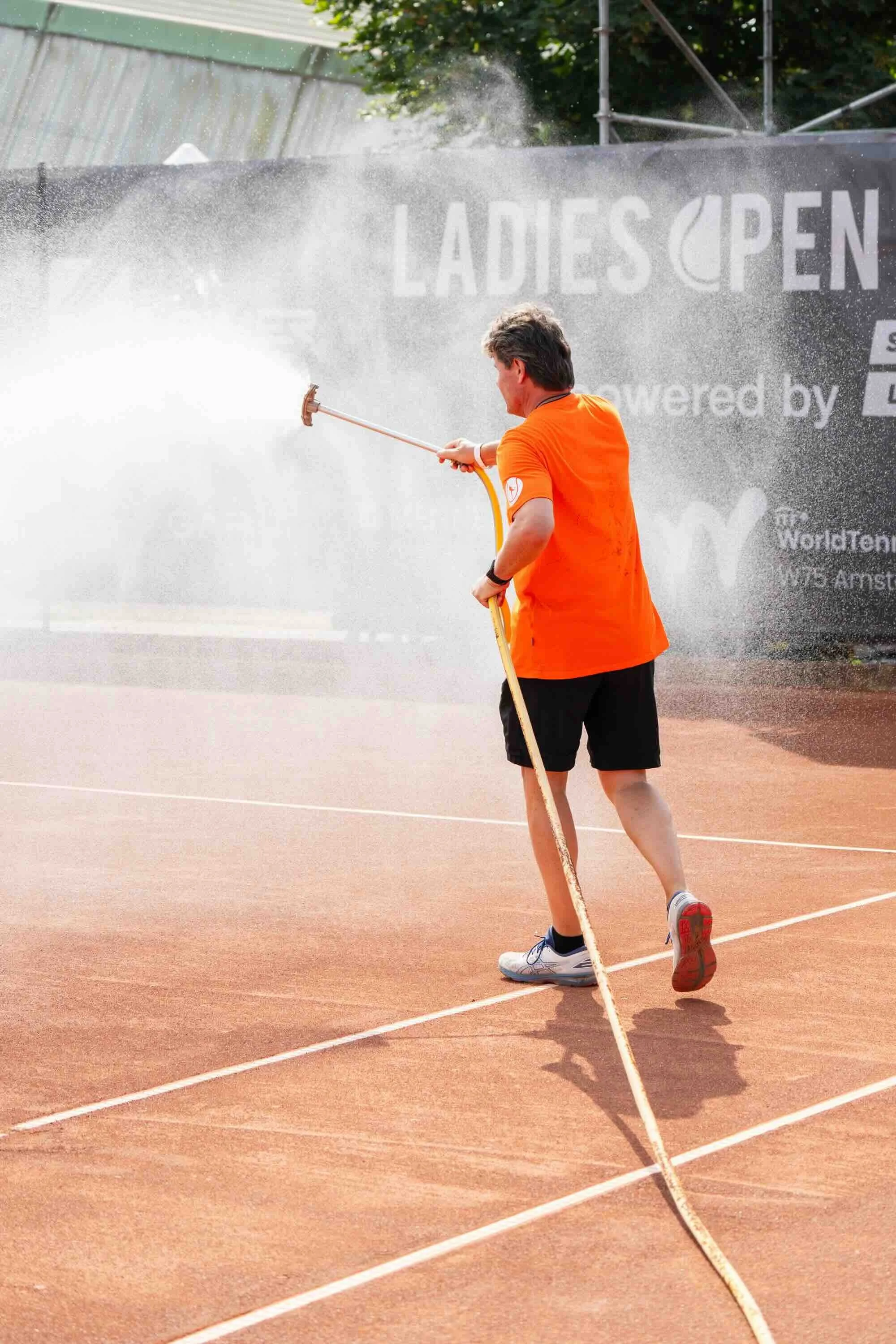 Ein Mann bewässert den Center Court.