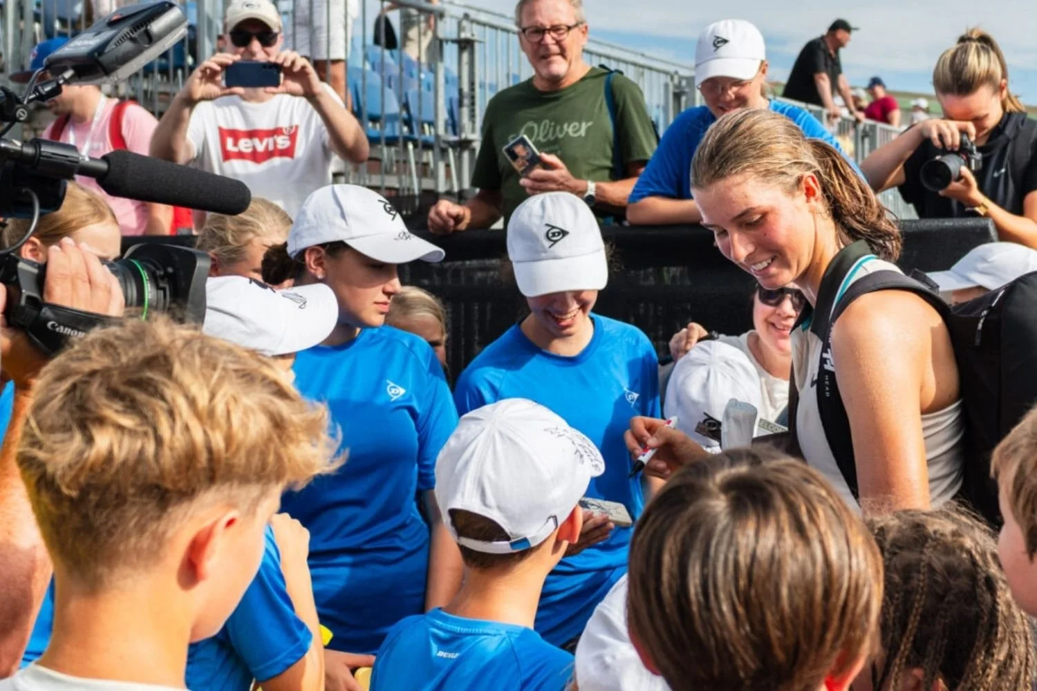 French Open Juniorinnen-Siegerin Lilli Tagger umgeben von Fans, die Fotos machen und Autogramme erbitten nach einem Sieg beim LADIES OPEN Amstetten 2025.